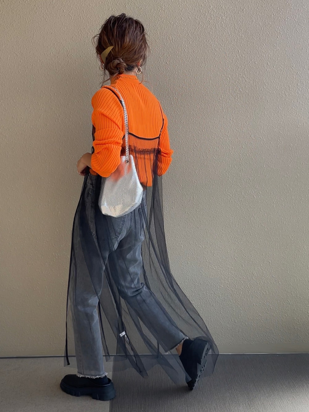 ブルー系のデニムパンツ、グリーン系のベスト、ブラック系のハンドバッグを着用したレディースの秋コーディネートの2枚目の写真