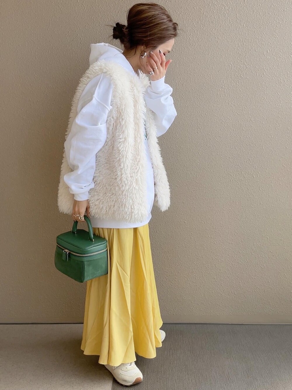 ホワイト系のパーカー、ホワイト系のベスト、ベージュ系のスニーカーを着用したレディースの冬コーディネートの3枚目の写真