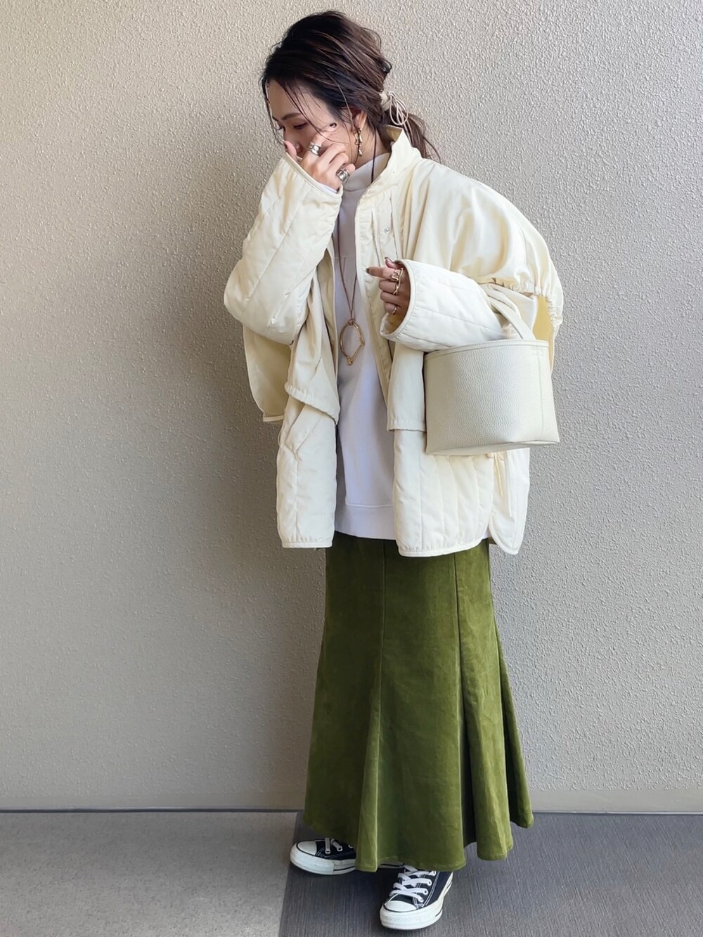 グリーン系のスカート、ホワイト系のスウェット、ブラック系のその他アウターを着用したレディースの冬コーディネートの5枚目の写真