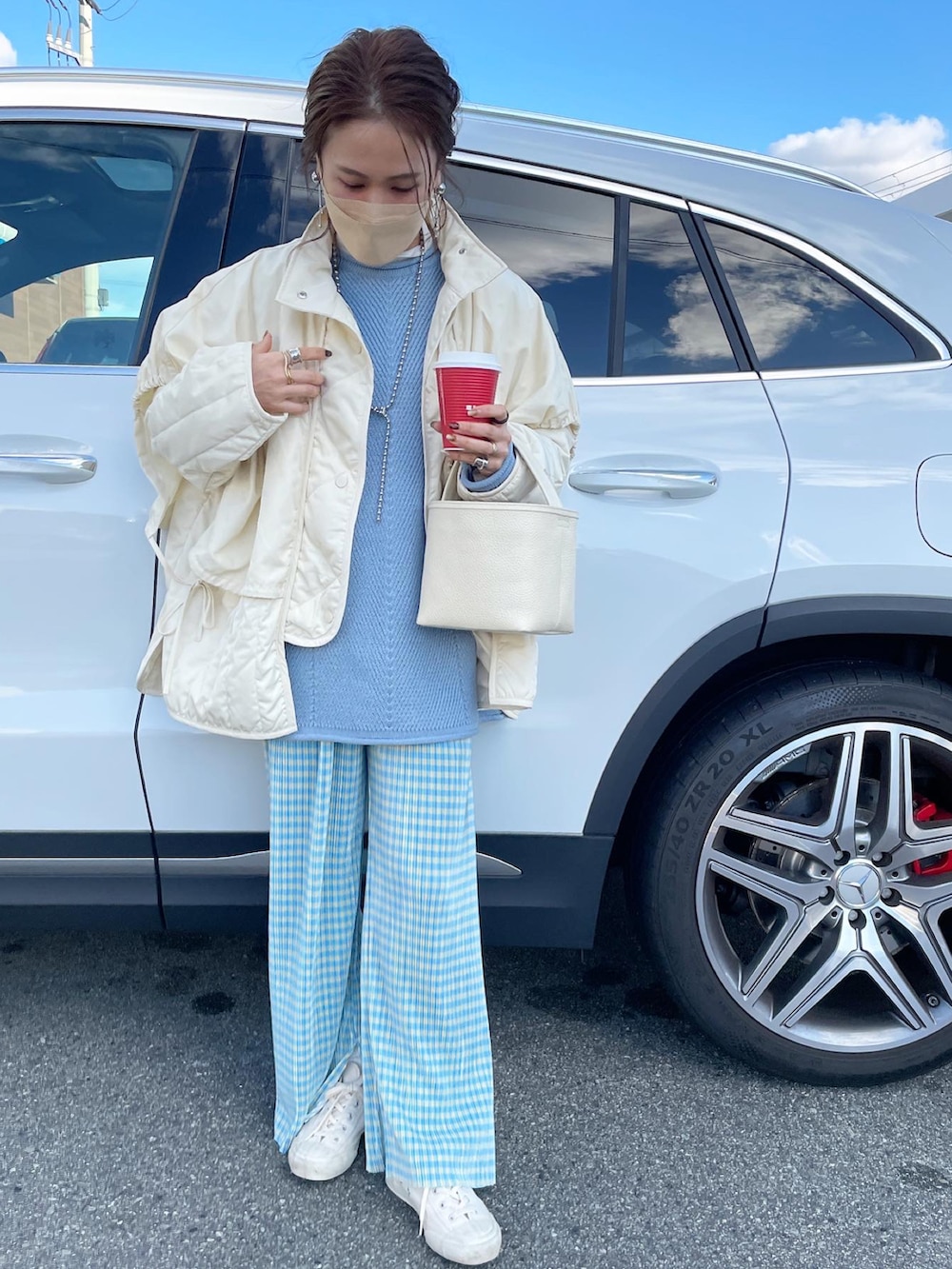 ホワイト系のダウンジャケット/コート、ブルー系のニット/セーター、ホワイト系のスニーカーを着用したレディースの冬コーディネートの2枚目の写真