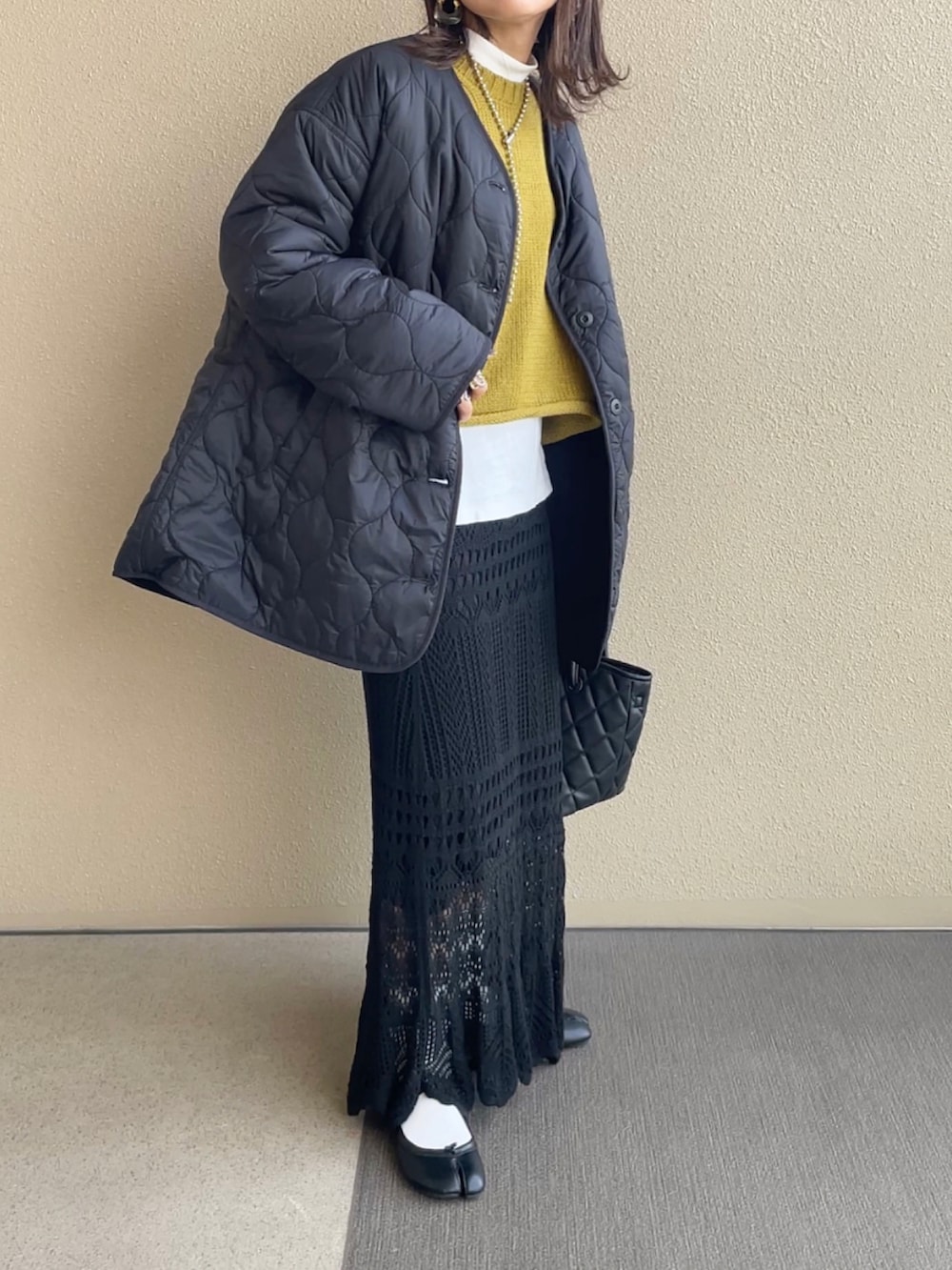 ブラック系のブルゾン、グリーン系のニット/セーター、ブラック系のトートバッグを着用したレディースの秋コーディネートの2枚目の写真