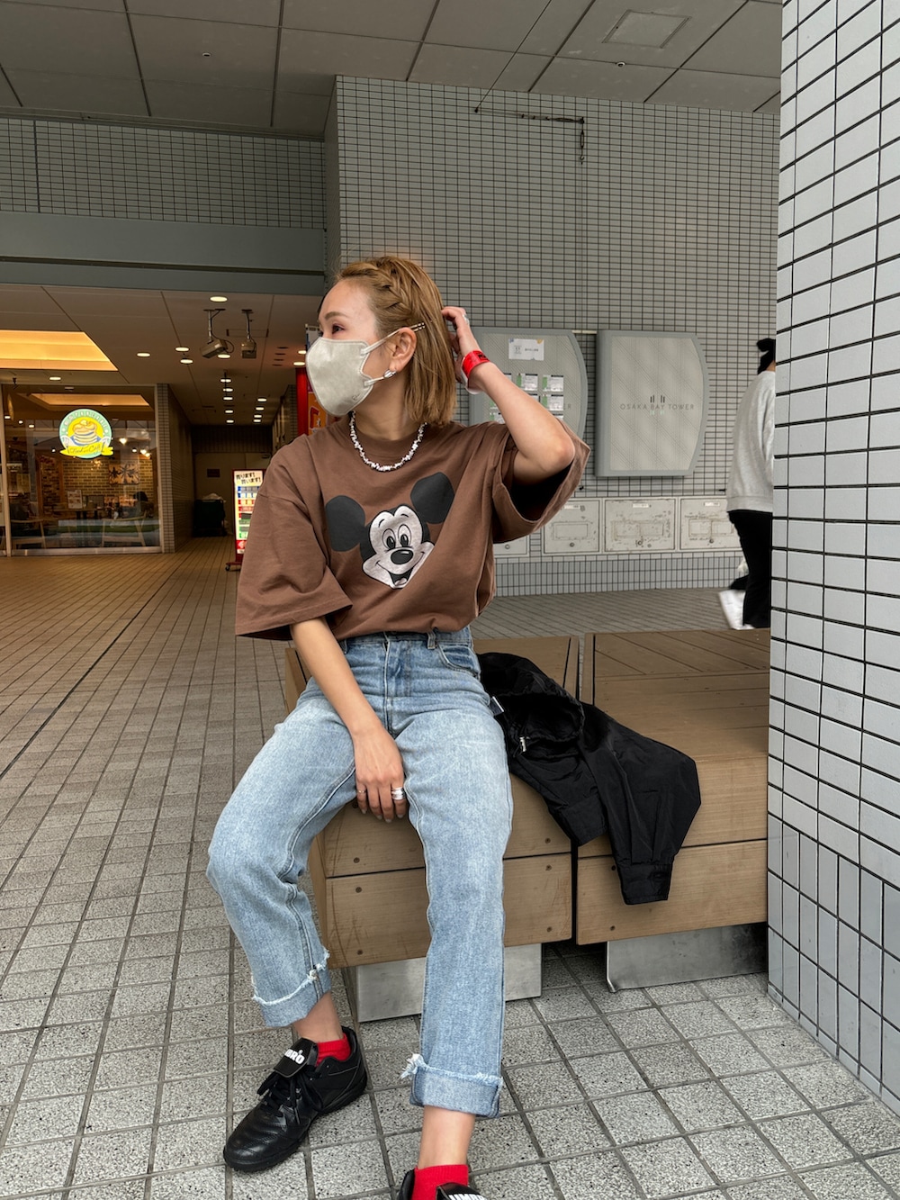 ブルー系のデニムパンツ、ブラック系のスニーカー、ブラウン系のTシャツ/カットソーを着用したレディースの春コーディネートの2枚目の写真