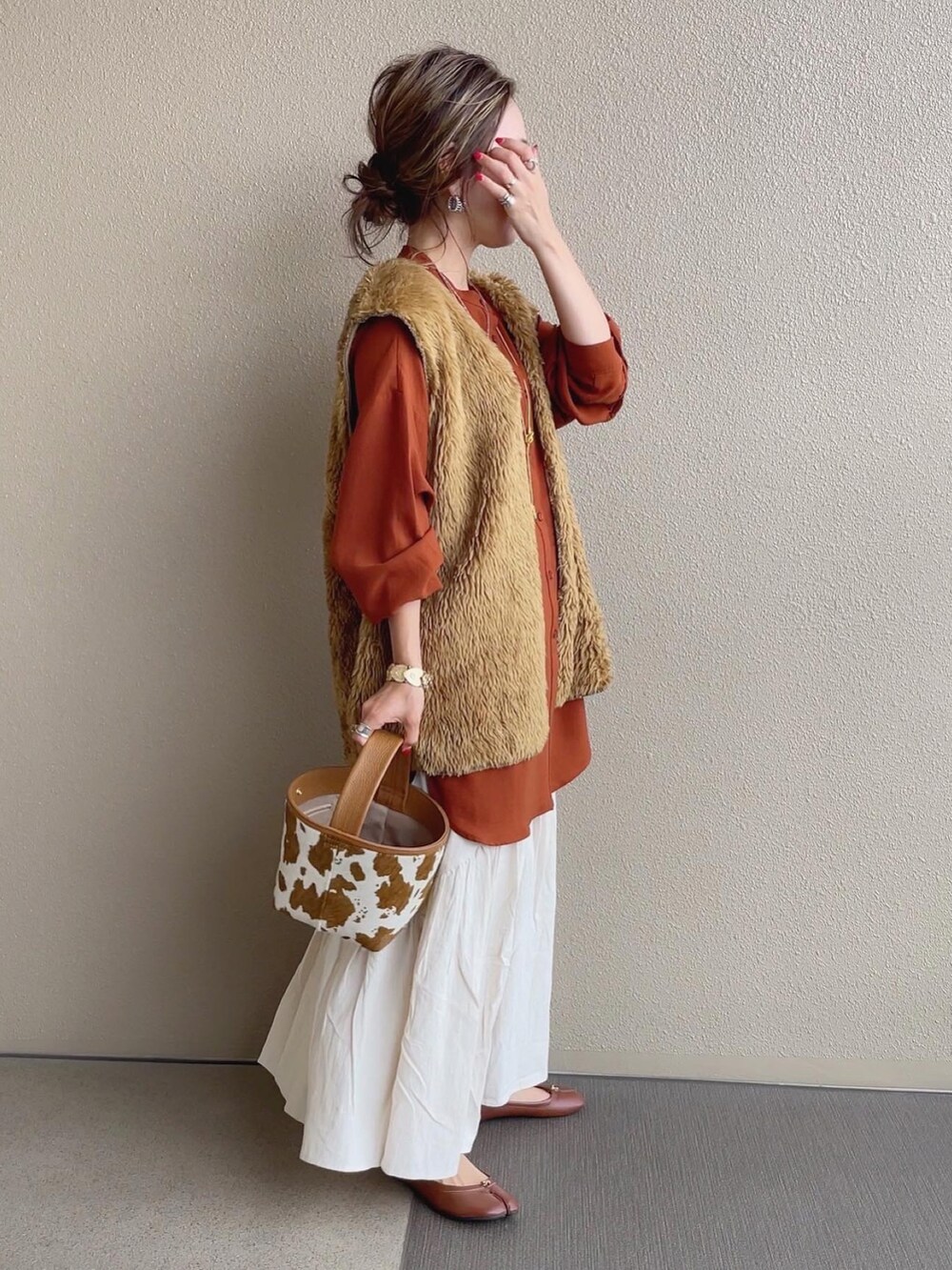 ホワイト系のスカート、ホワイト系のベスト、オレンジ系のTシャツ/カットソーを着用したレディースの夏コーディネートの3枚目の写真