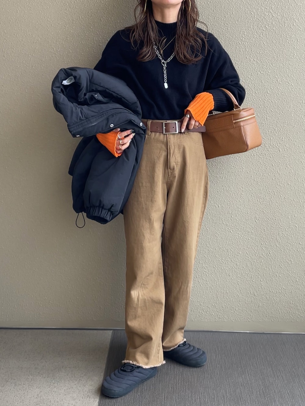 ブラック系のニット/セーター、ホワイト系のスカート、ブラウン系のデニムパンツを着用したレディースの冬コーディネートの2枚目の写真