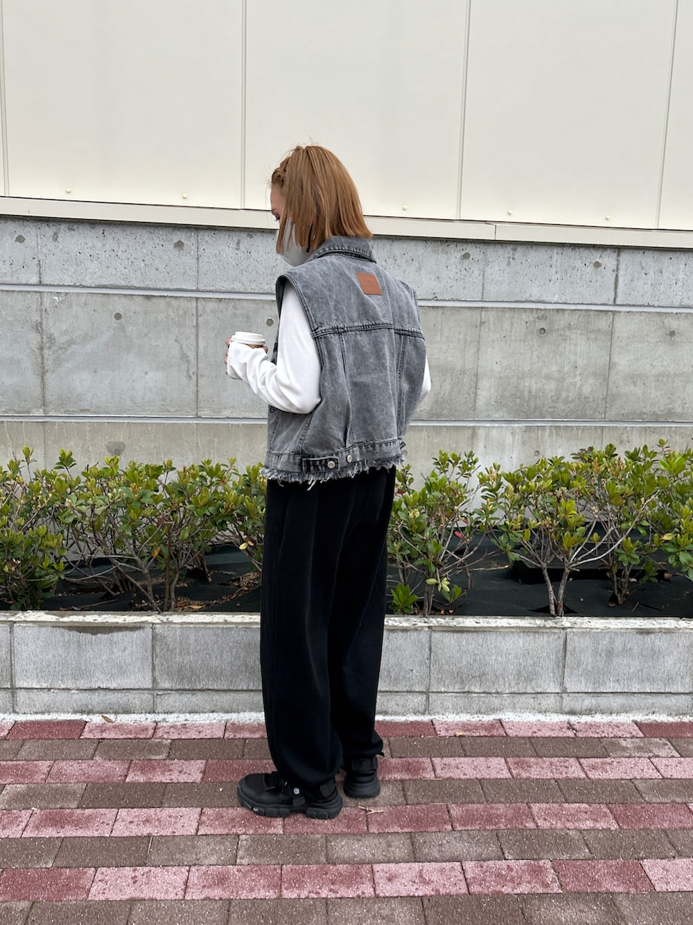 ホワイト系のTシャツ/カットソー、グレー系のベスト、ブラック系のサロペット/オーバーオールを着用したレディースの春コーディネートの3枚目の写真