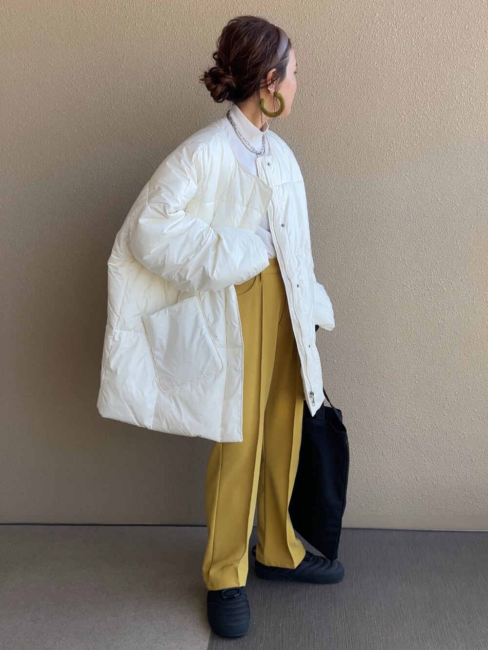 ホワイト系のダウンジャケット/コート、イエロー系のその他パンツ、ブラック系のトートバッグを着用したレディースの秋コーディネートの3枚目の写真