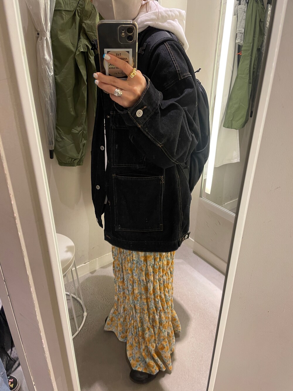 ホワイト系のパーカー、ブラック系のデニムジャケット、イエロー系のスカートを着用したレディースの冬コーディネートの3枚目の写真