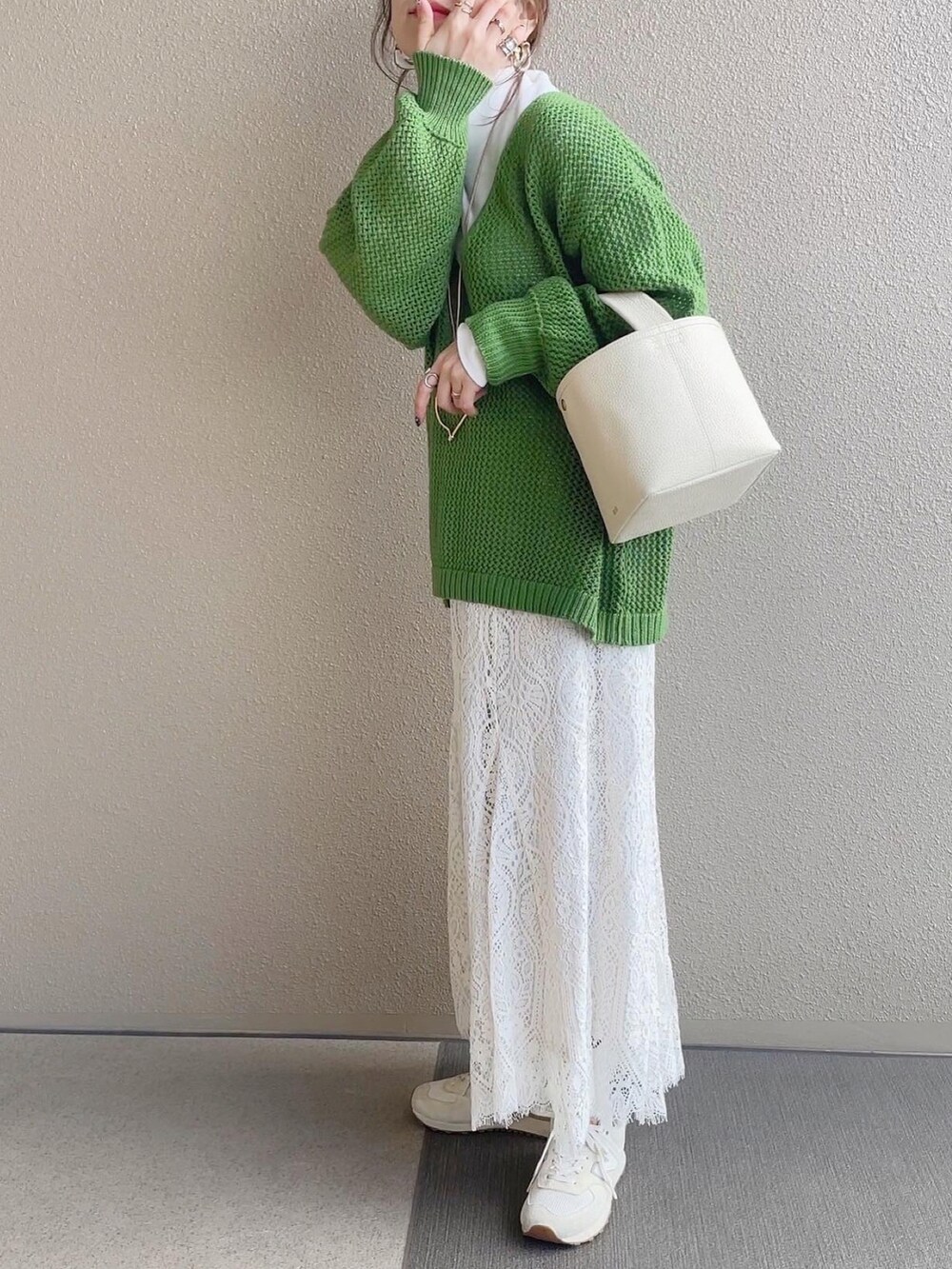 グリーン系のニット/セーター、ホワイト系のスカート、ベージュ系のスニーカーを着用したレディースの冬コーディネートの3枚目の写真
