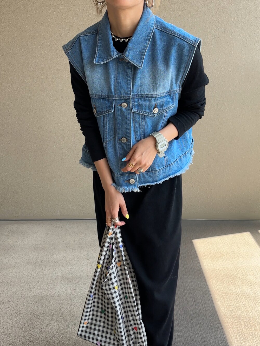 ブルー系のベスト、ブラック系のワンピースを着用したレディースの春コーディネートの2枚目の写真