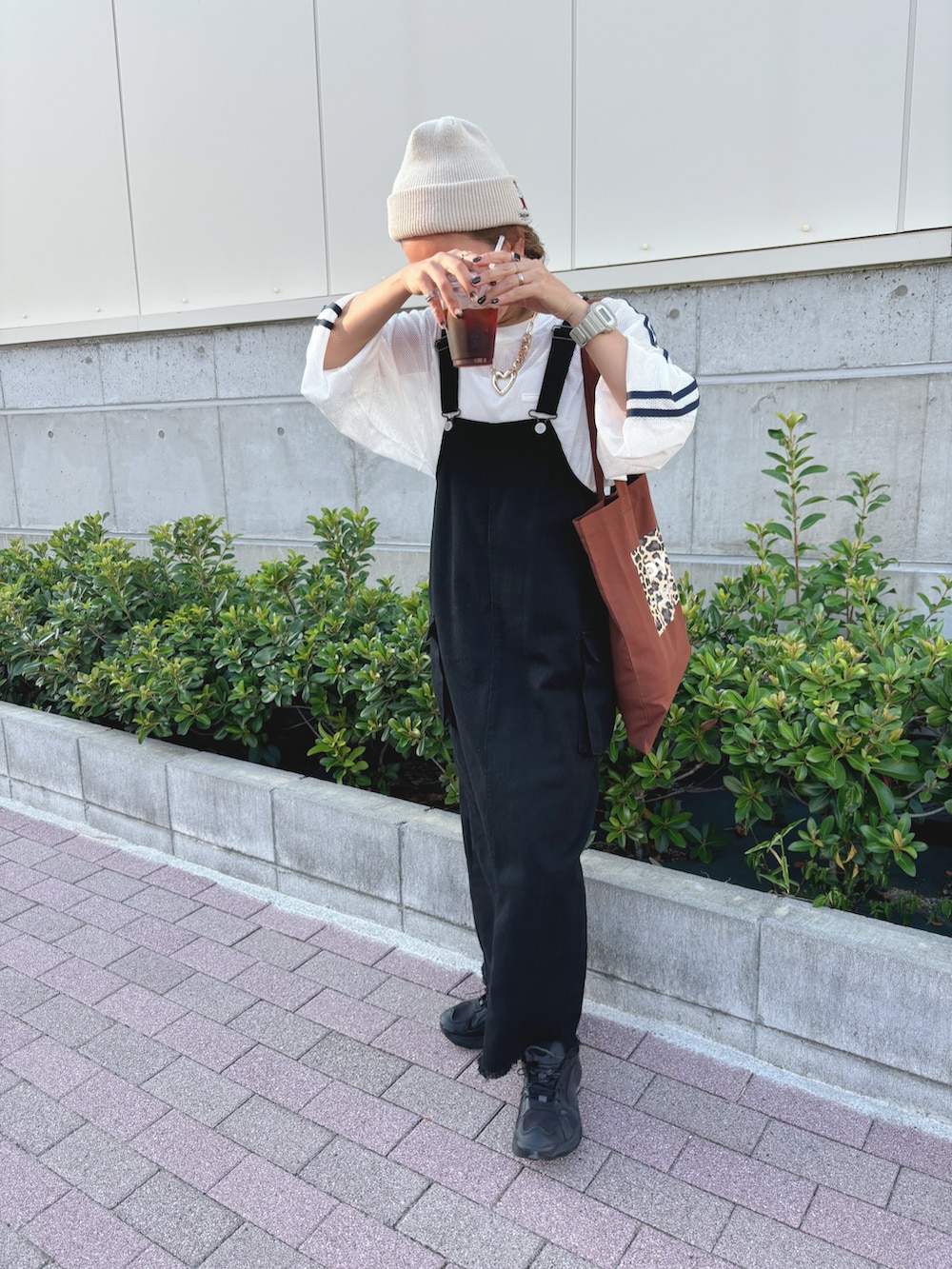 ブラック系のジャンパースカート、ブラック系のスニーカー、ベージュ系のニットキャップ/ビーニーを着用したレディースの秋コーディネートの2枚目の写真