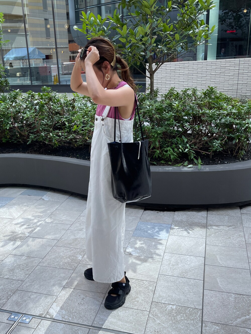 ピンク系のTシャツ/カットソー、ホワイト系のジャンパースカート、ブラック系のショルダーバッグを着用したレディースの夏コーディネートの4枚目の写真