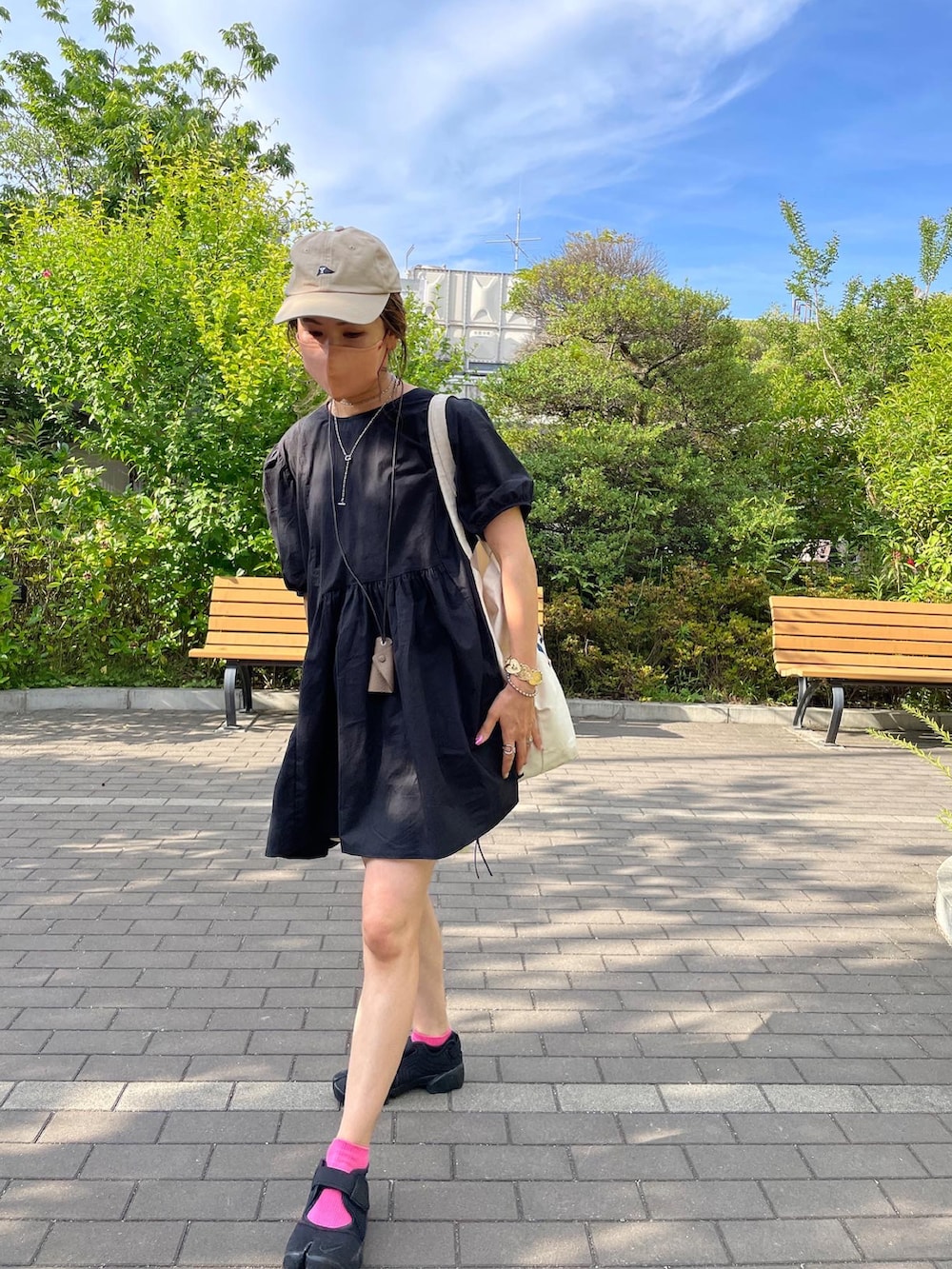 ブラック系のワンピース、ホワイト系のトートバッグ、ブラック系のサンダルを着用したレディースの夏コーディネートの2枚目の写真