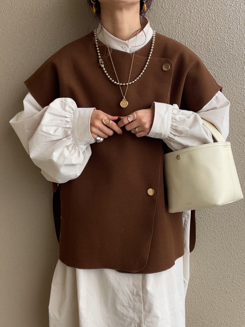 ホワイト系のワンピース、ブラウン系のベスト、ベージュ系のスニーカーを着用したレディースの秋コーディネートの3枚目の写真