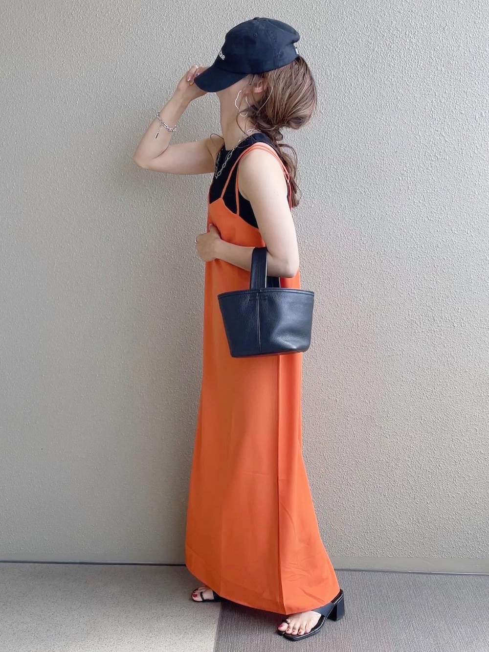 オレンジ系のワンピース、ブラック系のタンクトップ、ホワイト系のシャツ/ブラウスを着用したレディースの春コーディネートの3枚目の写真