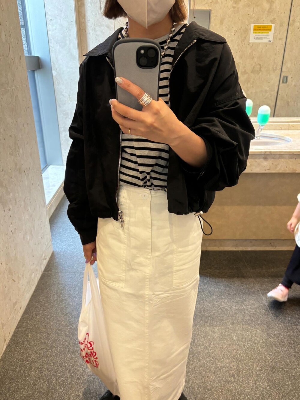 グレー系のTシャツ/カットソー、ホワイト系のスカート、ブラック系のナイロンジャケットを着用したレディースの春コーディネートの5枚目の写真