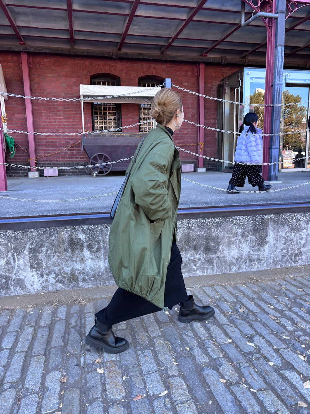 グリーン系のモッズコート、ブラック系のワンピースを着用したレディースの冬コーディネートの2枚目の写真