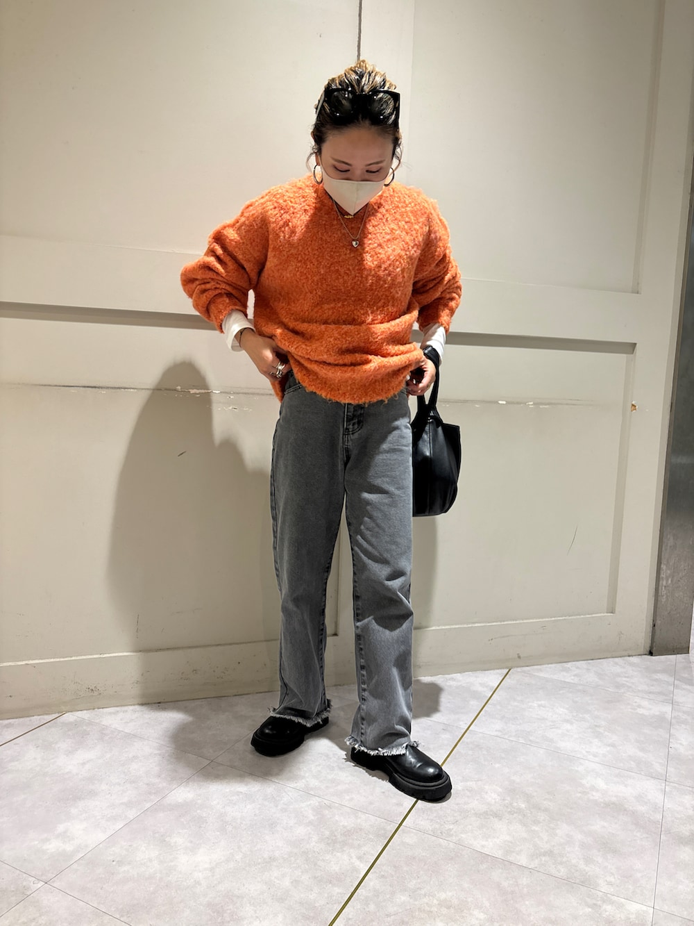 オレンジ系のニット/セーター、ブラック系のデニムパンツを着用したレディースの冬コーディネートの4枚目の写真
