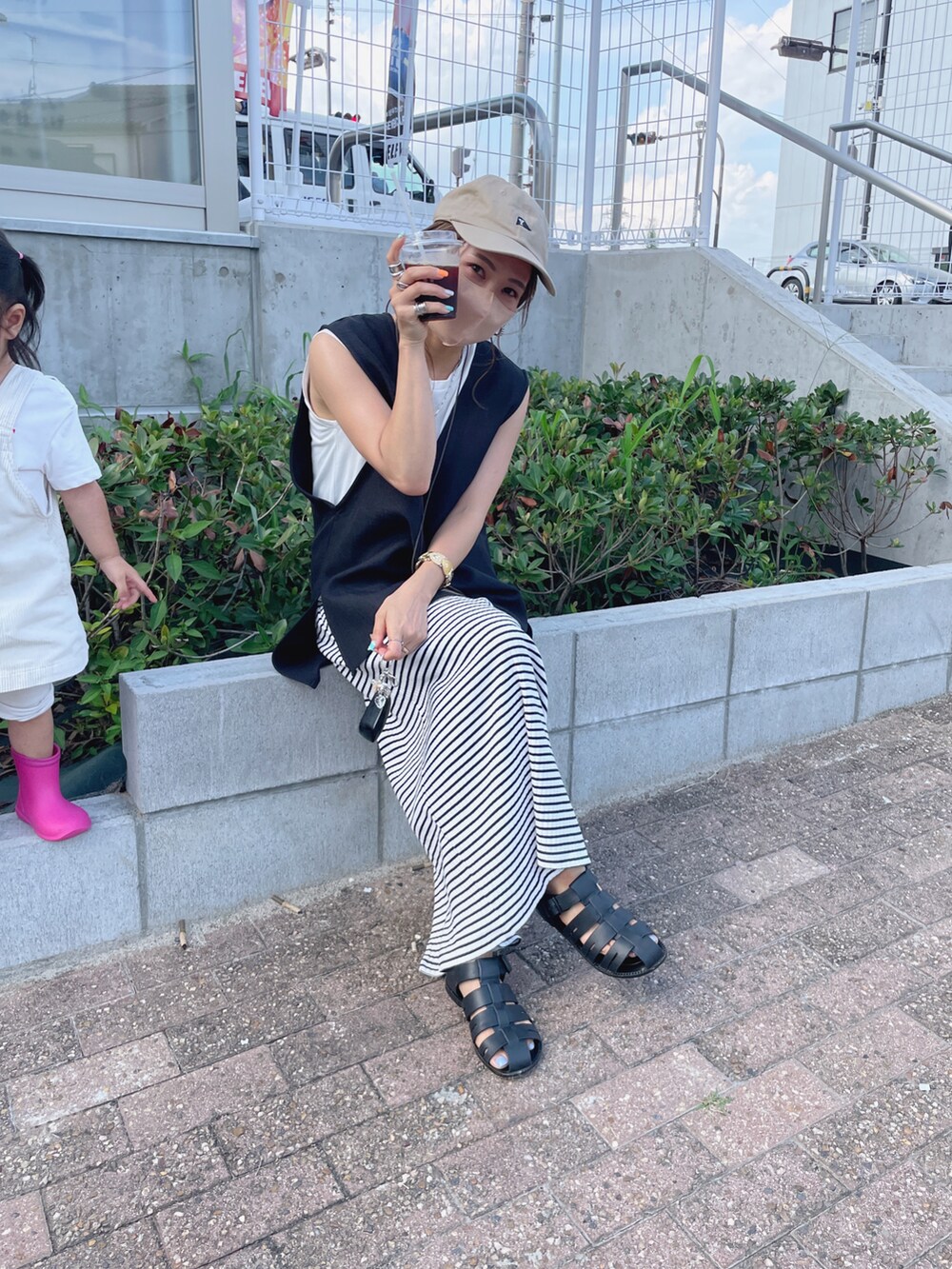 ブラック系のベスト、ブラック系のサンダル、その他のスカートを着用したレディースの夏コーディネートの2枚目の写真