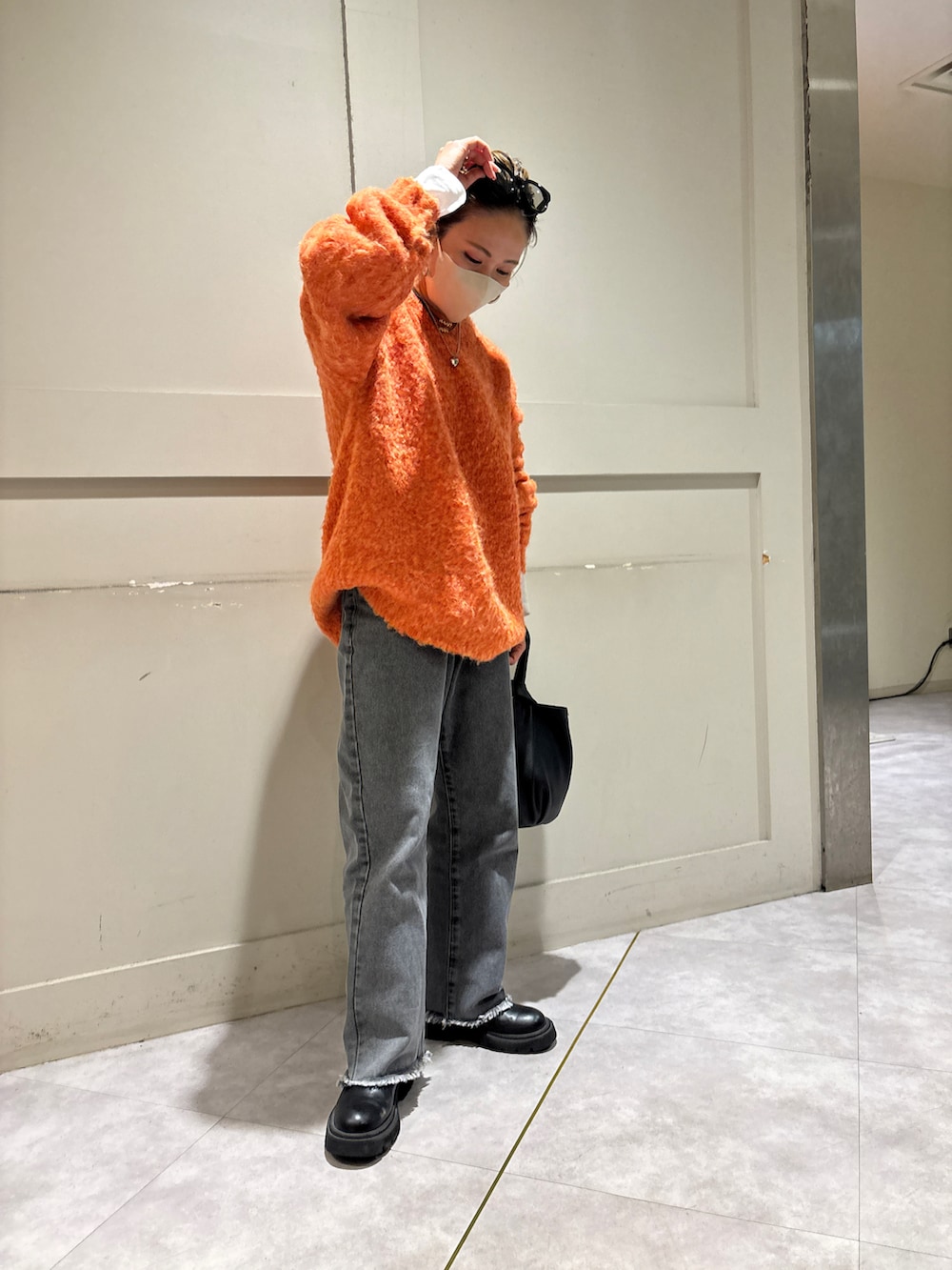 オレンジ系のニット/セーター、ブラック系のデニムパンツを着用したレディースの冬コーディネートの2枚目の写真