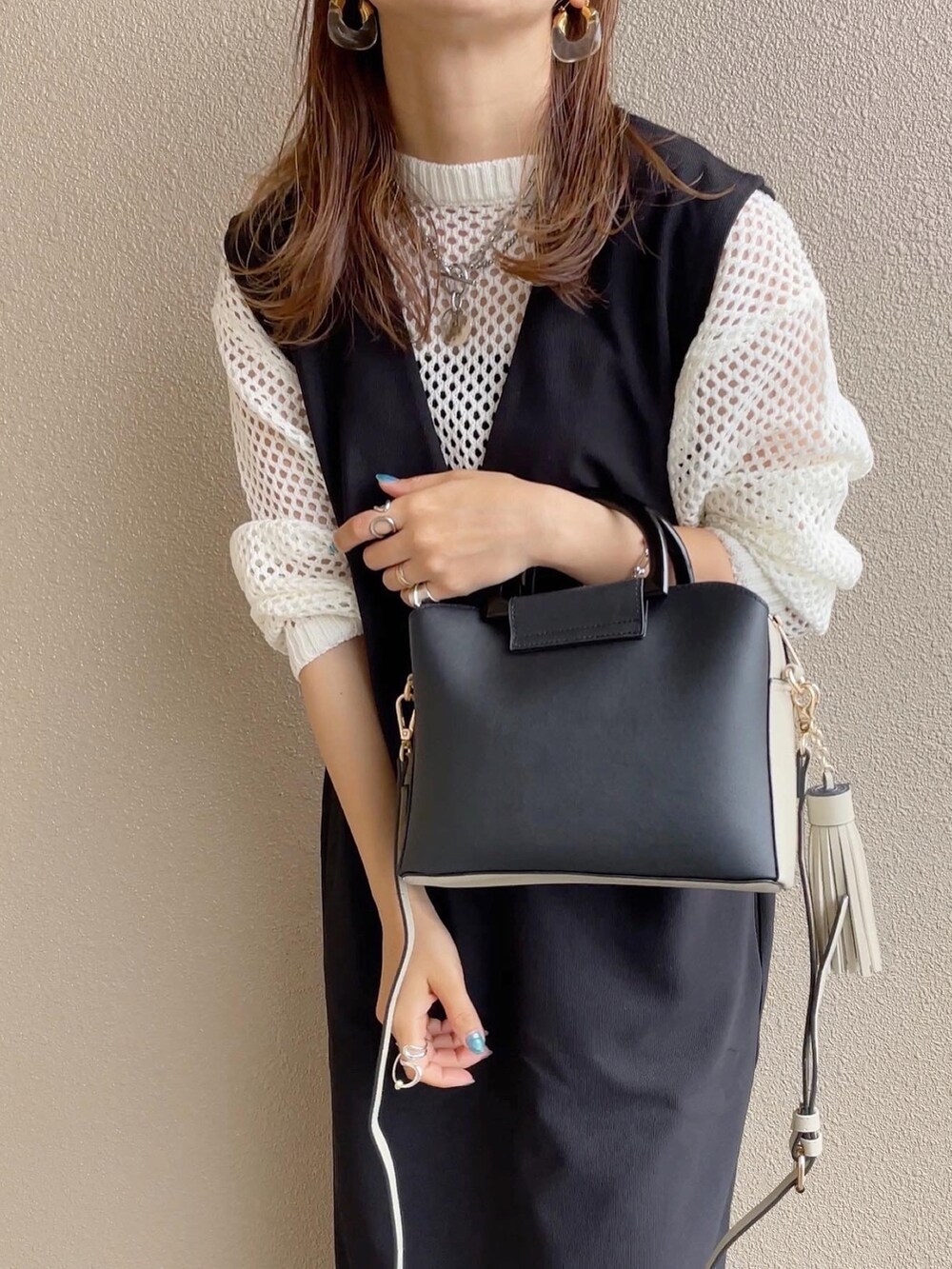 ブラック系のジャンパースカート、ホワイト系のトップス、ホワイト系のニット/セーターを着用したレディースの春コーディネートの5枚目の写真