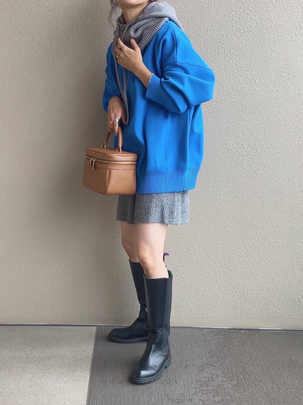 ブルー系のニット/セーター、ベージュ系のスカート、ホワイト系のベストを着用したレディースの秋コーディネートの3枚目の写真