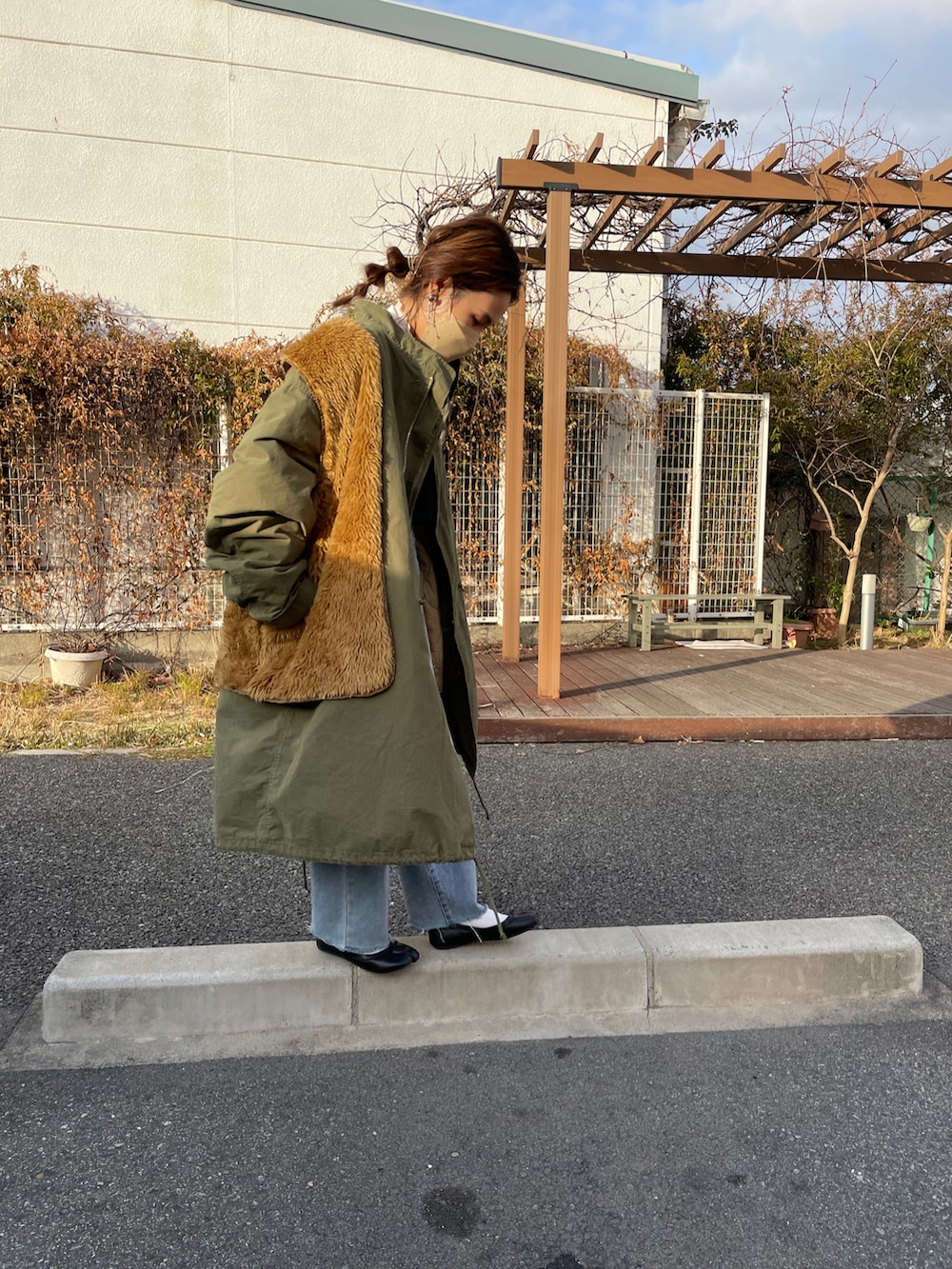 グリーン系のモッズコート、ブラウン系のベスト、ブラック系のニット/セーターを着用したレディースの冬コーディネートの3枚目の写真