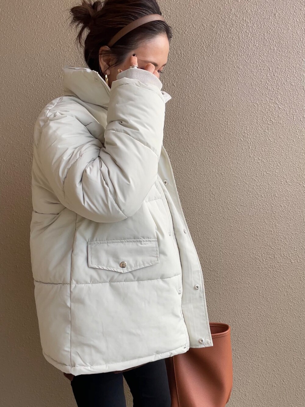 ホワイト系のダウンジャケット/コート、ブラック系のブーツ、ブラウン系のバッグを着用したレディースの冬コーディネートの3枚目の写真