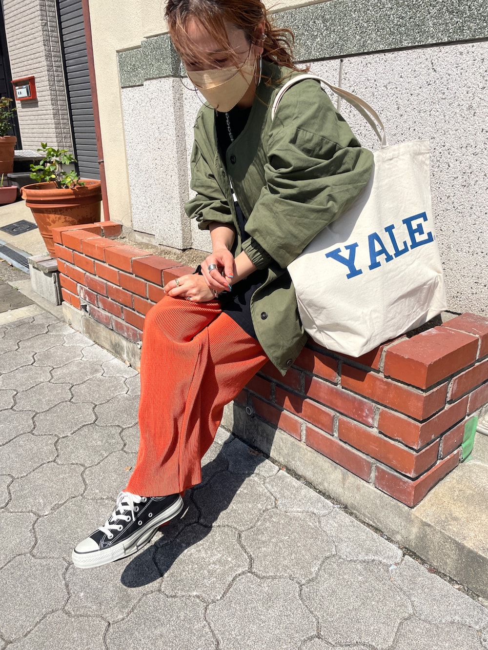 ブラック系のTシャツ/カットソー、オレンジ系のその他パンツ、ホワイト系のトートバッグを着用したレディースの春コーディネートの2枚目の写真