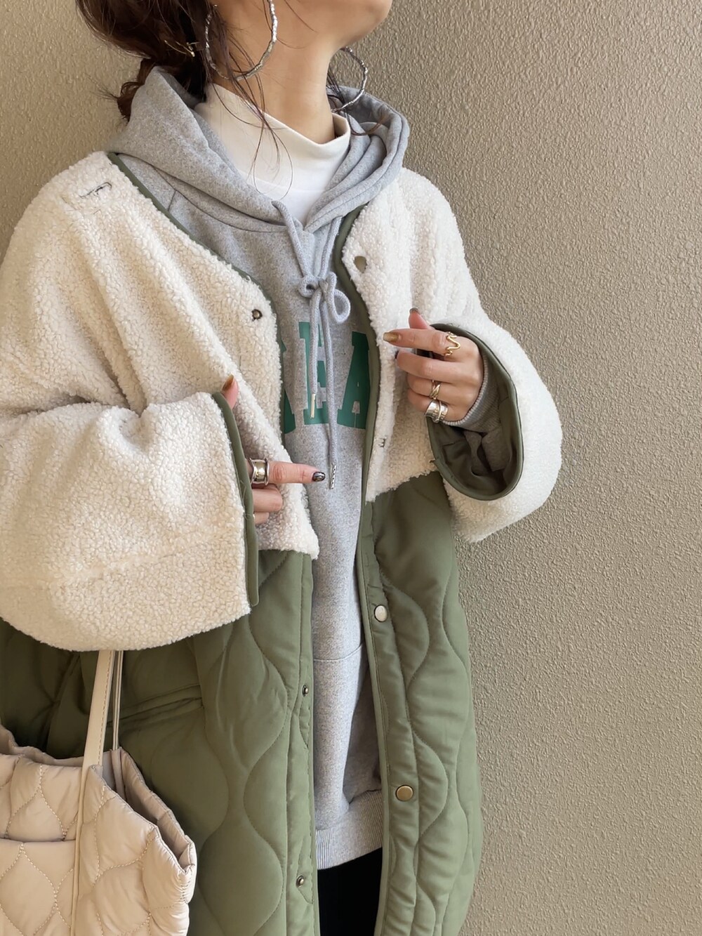 グリーン系のノーカラージャケット、グレー系のパーカー、ベージュ系のトートバッグを着用したレディースの冬コーディネートの5枚目の写真