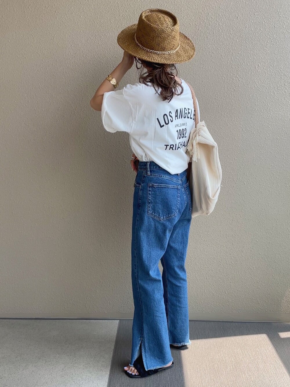 ホワイト系のTシャツ/カットソー、ホワイト系のトートバッグ、ブルー系のデニムパンツを着用したレディースの夏コーディネートの3枚目の写真