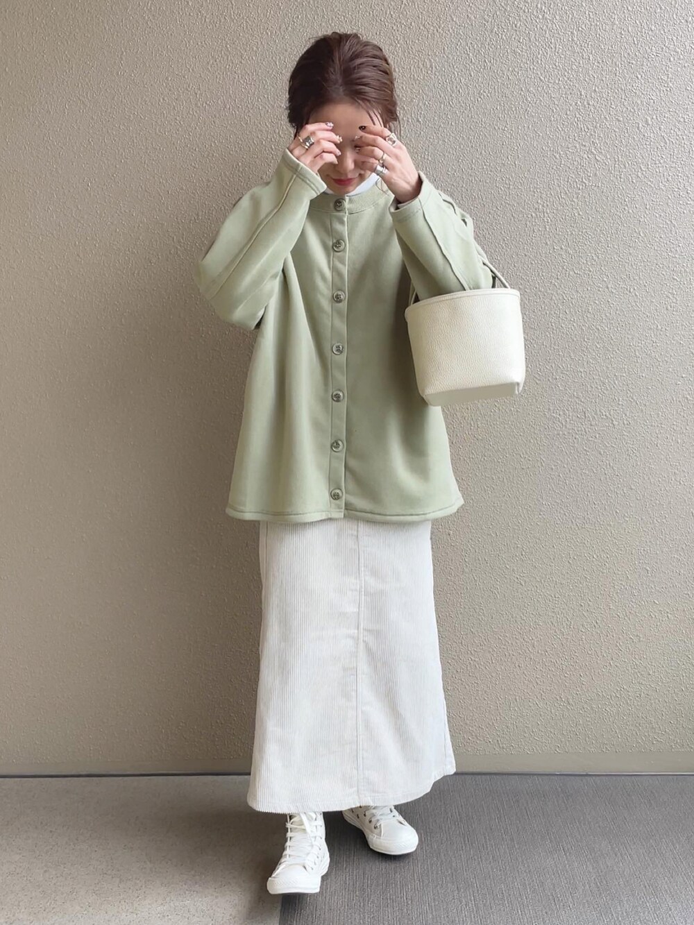 グリーン系のカーディガン/ボレロ、ホワイト系のスカート、ホワイト系のスニーカーを着用したレディースの冬コーディネートの2枚目の写真