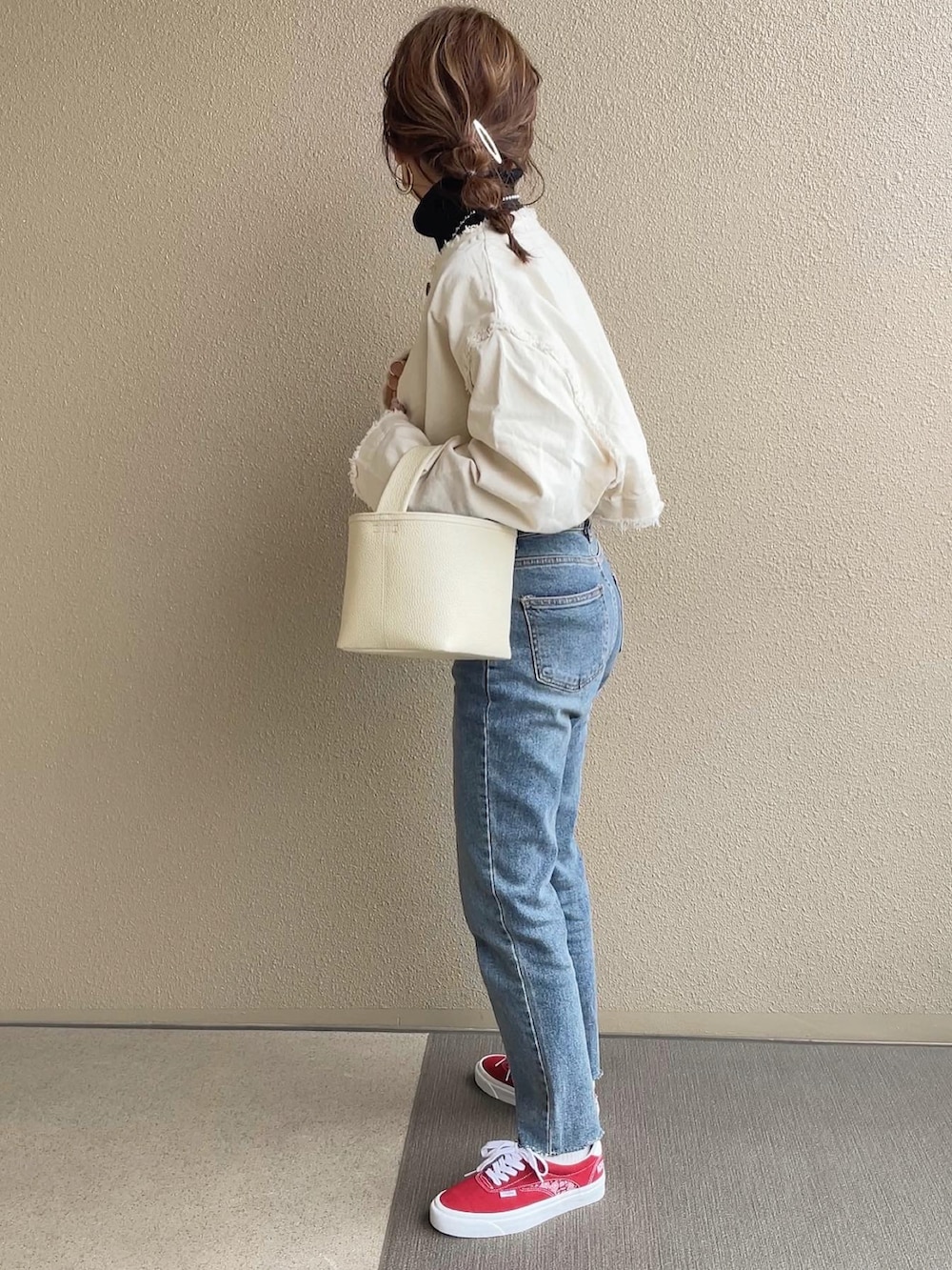 ホワイト系のデニムジャケット、ブルー系のデニムパンツ、レッド系のスニーカーを着用したレディースの冬コーディネートの4枚目の写真