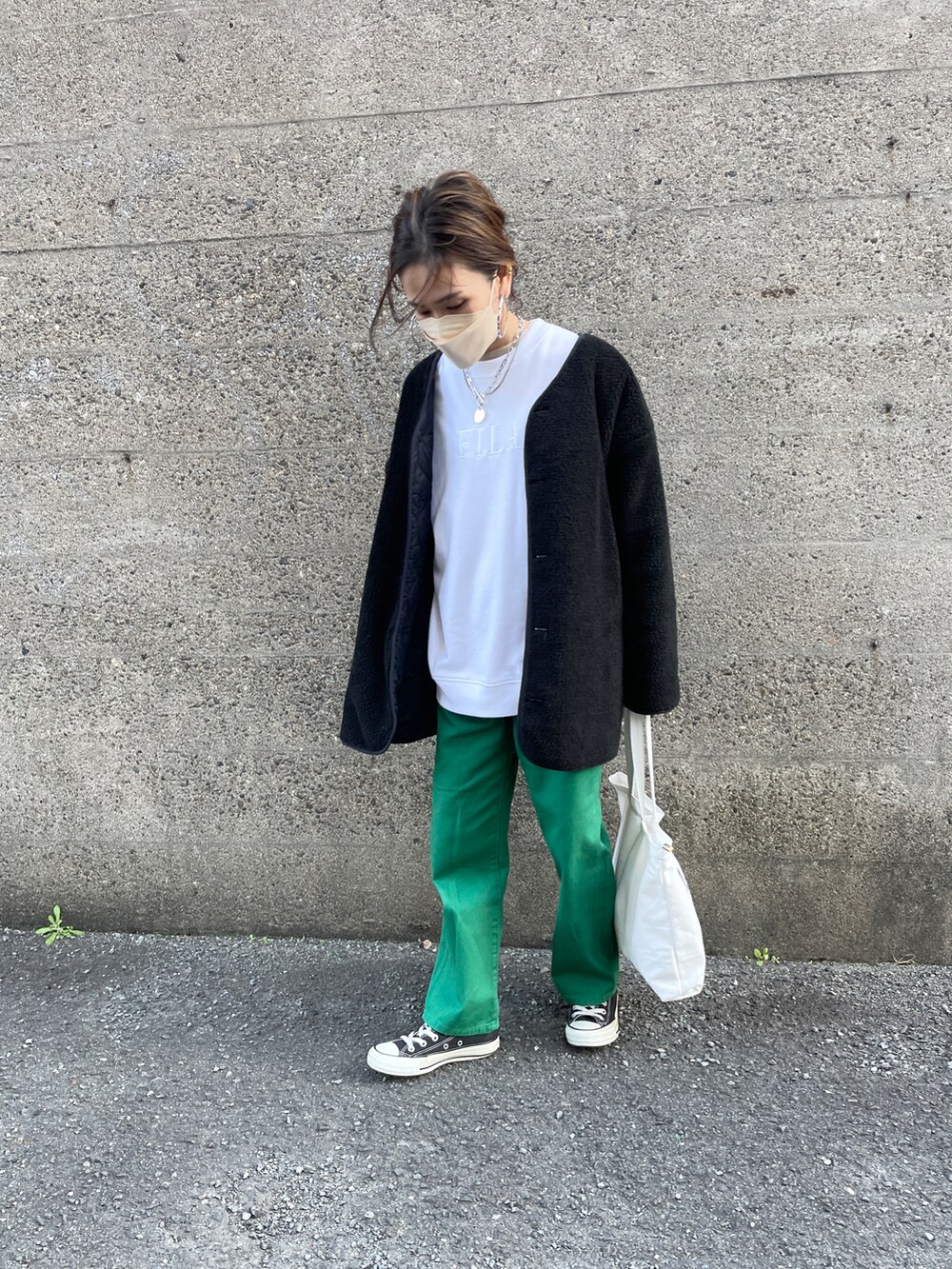 グリーン系のデニムパンツ、ブラック系のブルゾン、ホワイト系のスウェットを着用したレディースの冬コーディネートの2枚目の写真