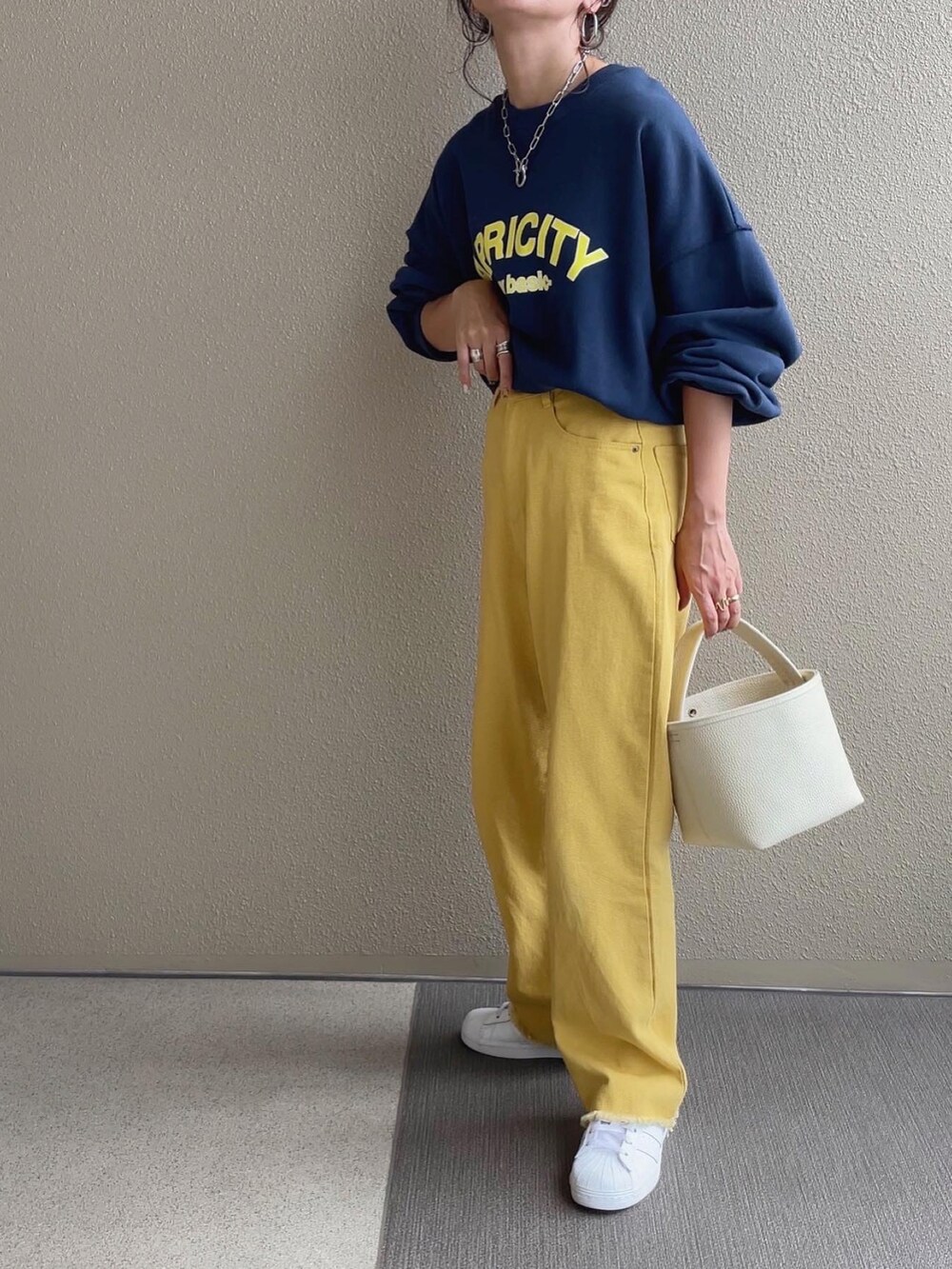 ピンク系のスウェット、ホワイト系のベスト、ブルー系のショルダーバッグを着用したレディースの秋コーディネートの3枚目の写真