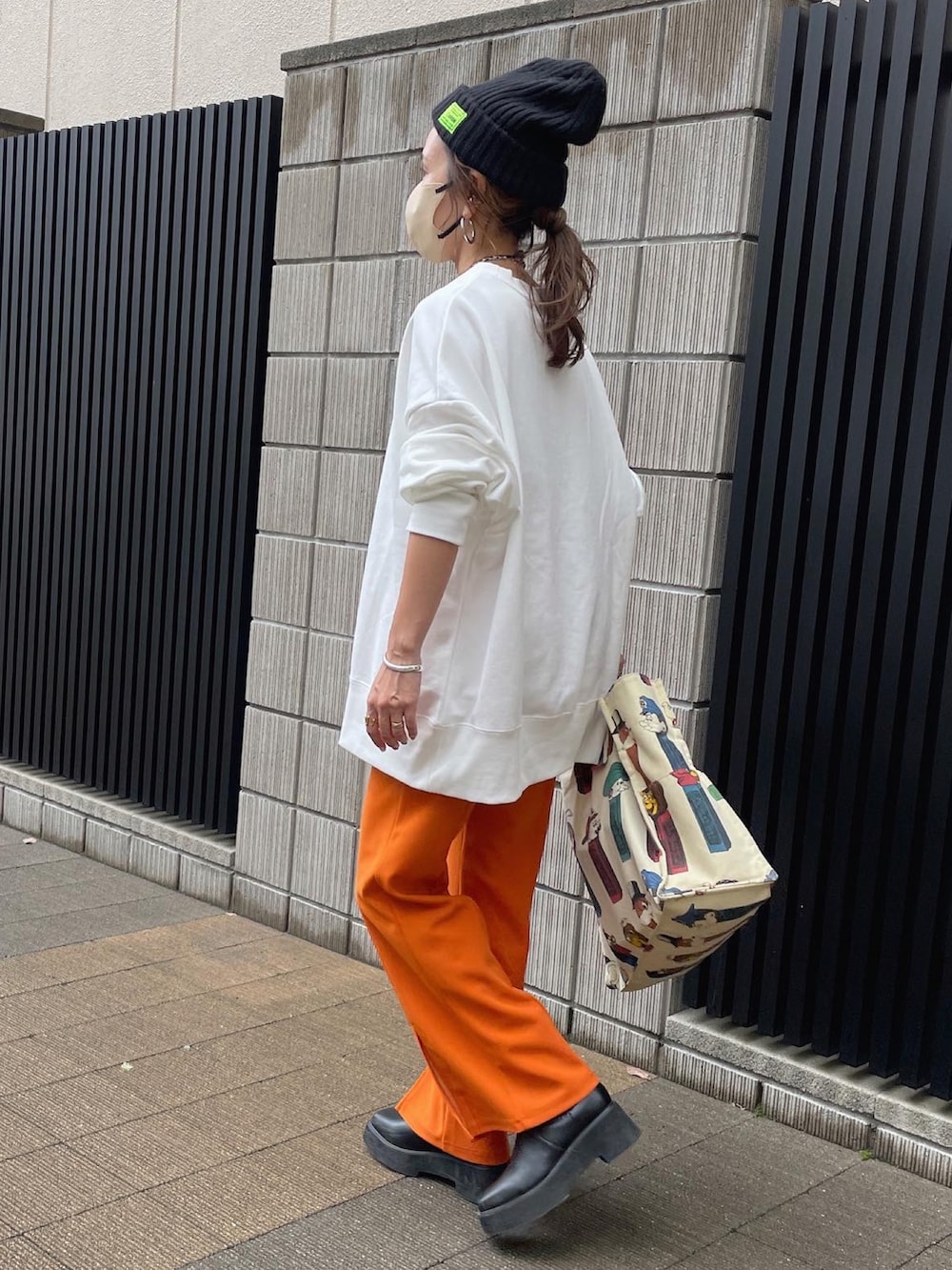 ホワイト系のスウェット、オレンジ系のスラックス、ブラック系のブーツを着用したレディースの秋コーディネートの3枚目の写真