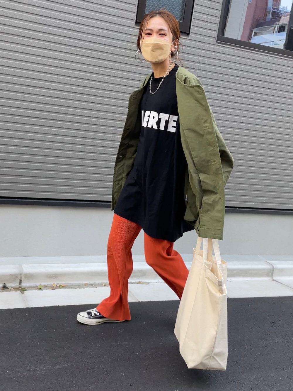 ブラック系のTシャツ/カットソー、オレンジ系のその他パンツ、ホワイト系のトートバッグを着用したレディースの春コーディネートの3枚目の写真