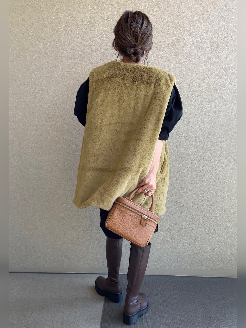 ブラック系のワンピース、イエロー系のベスト、ブラウン系のブーツを着用したレディースの秋コーディネートの5枚目の写真