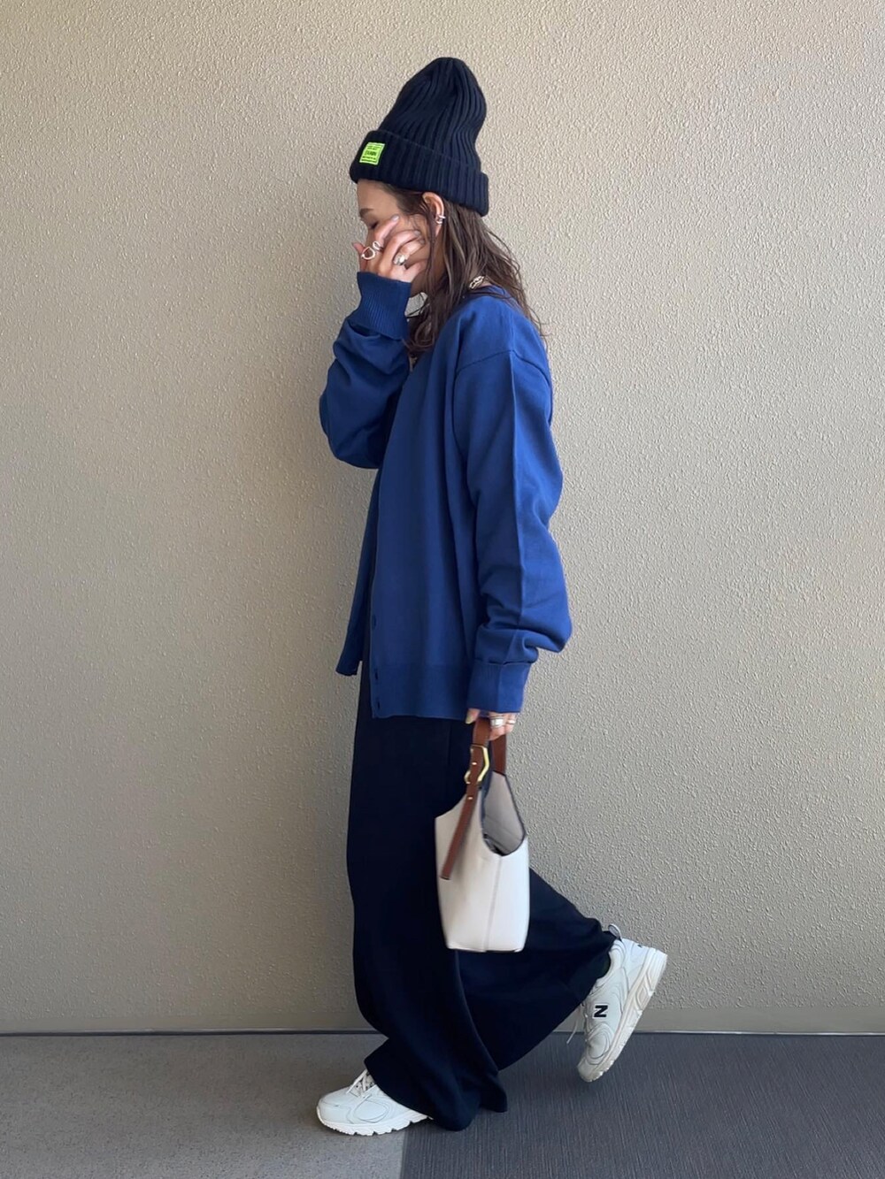 ブルー系のカーディガン/ボレロ、ブラック系のサロペット/オーバーオール、ホワイト系のスニーカーを着用したレディースの秋コーディネートの2枚目の写真