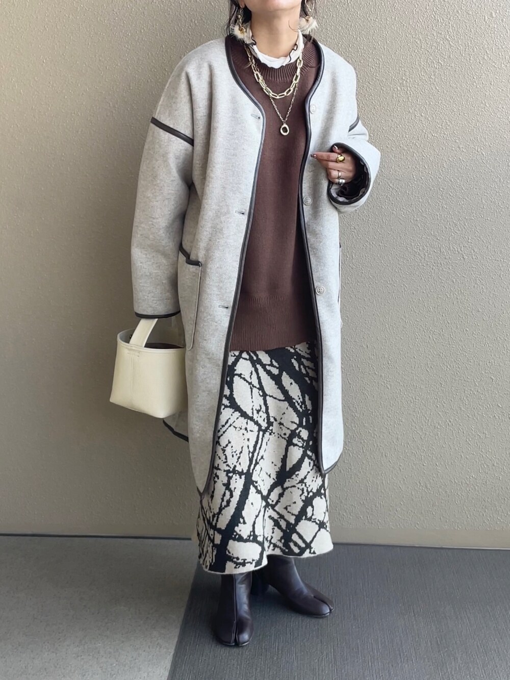 ブラウン系のニット/セーター、ベージュ系のスカート、ベージュ系のその他アウターを着用したレディースの冬コーディネートの2枚目の写真