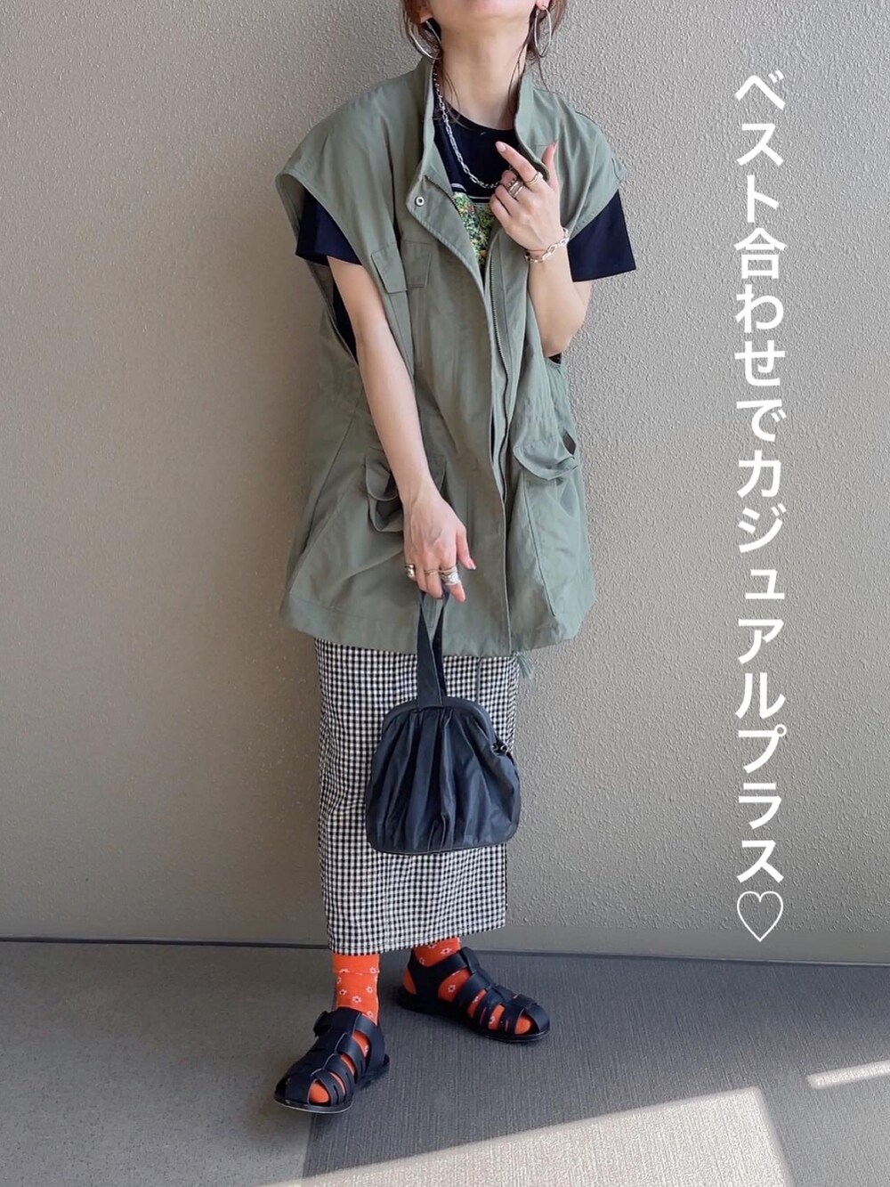 ブラック系のTシャツ/カットソー、ブラック系のスカート、グリーン系のベストを着用したレディースの春コーディネートの4枚目の写真