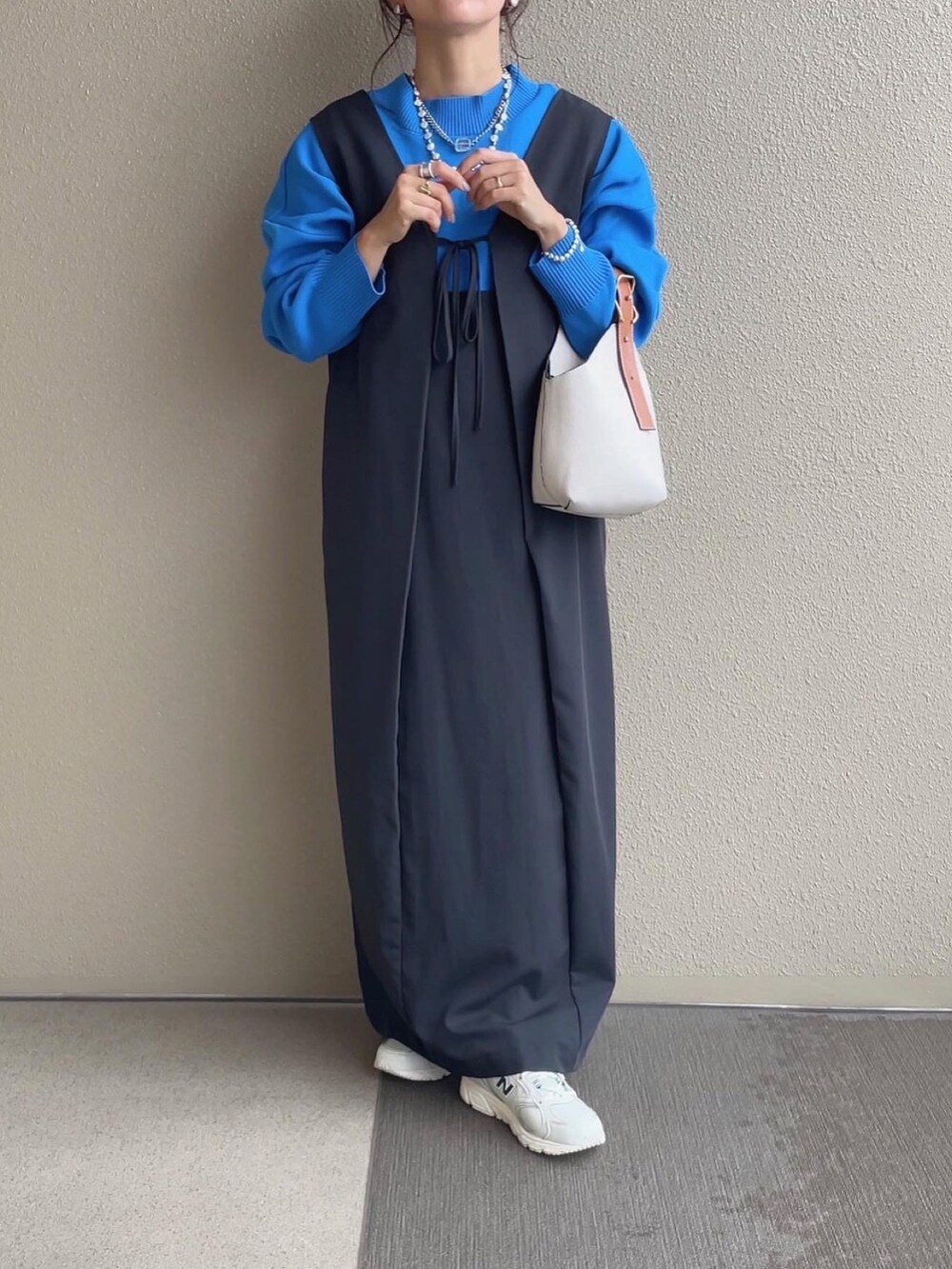 ブルー系のニット/セーター、ベージュ系のスカート、ホワイト系のベストを着用したレディースの秋コーディネートの2枚目の写真