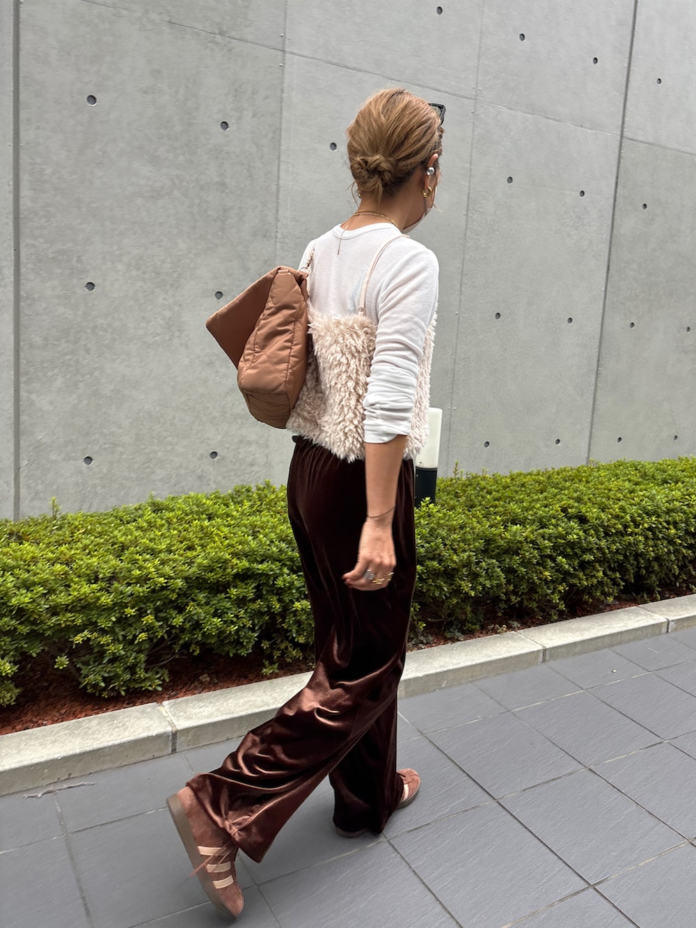 ホワイト系のベスト、ブラウン系のスニーカー、ブラウン系のパンツを着用したレディースの秋コーディネートの2枚目の写真