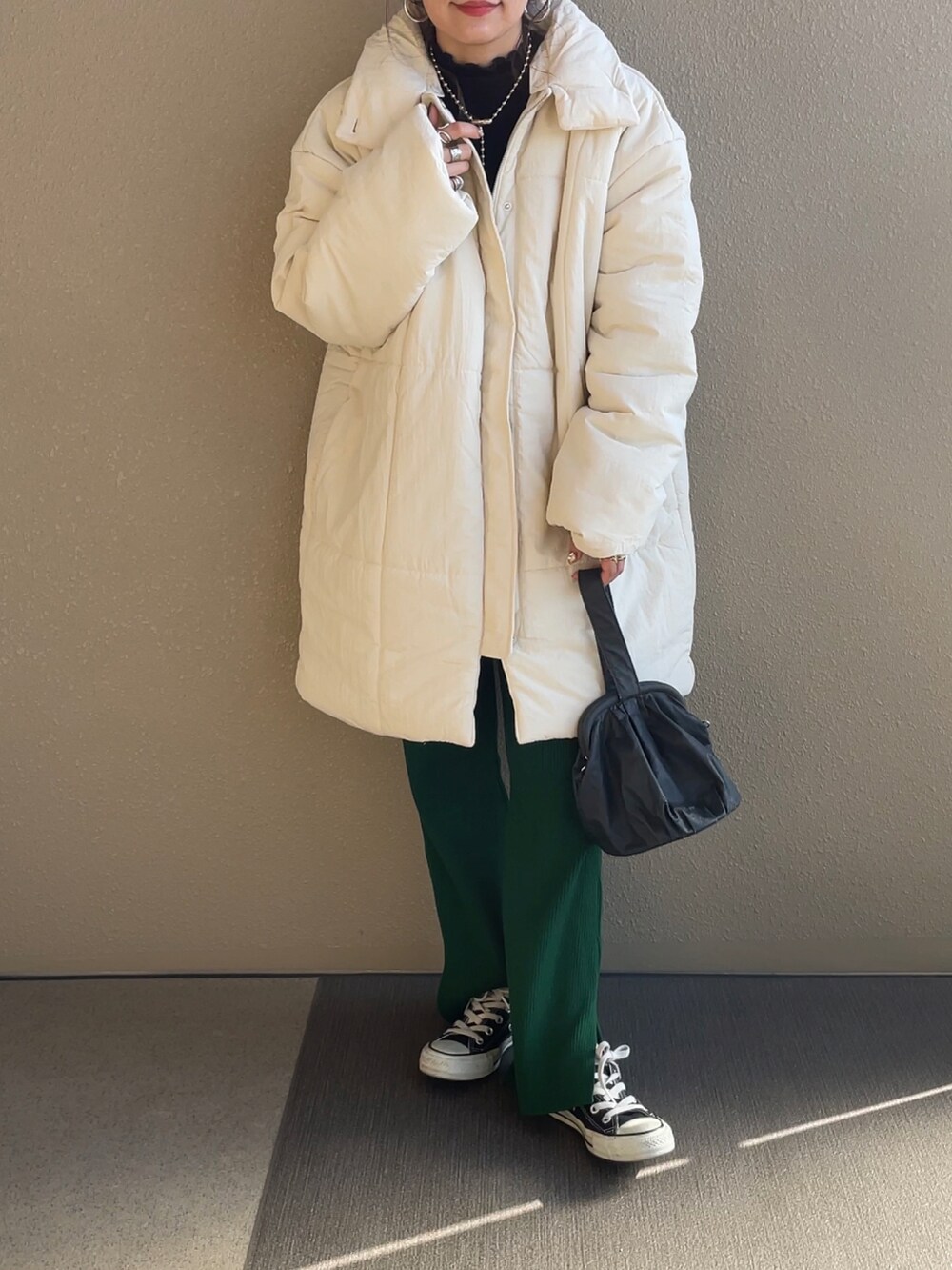 ホワイト系のダウンジャケット/コート、ブラック系のニット/セーター、グリーン系のパンツを着用したレディースの秋コーディネートの3枚目の写真