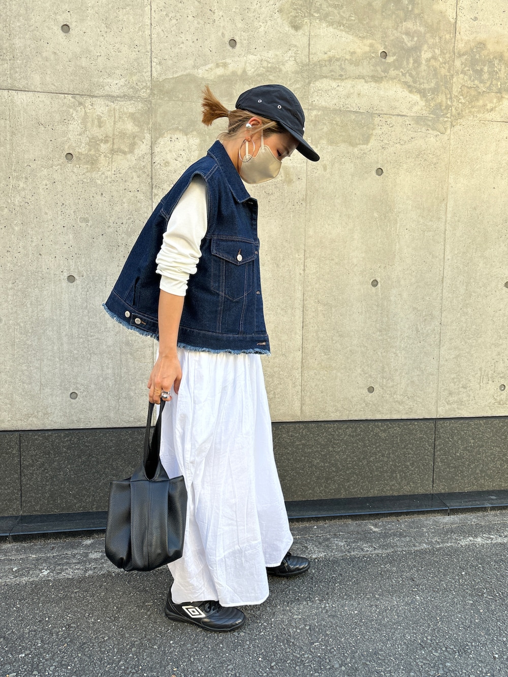 ブルー系のベスト、ホワイト系のワンピース、ブラック系のキャップを着用したレディースの春コーディネートの3枚目の写真