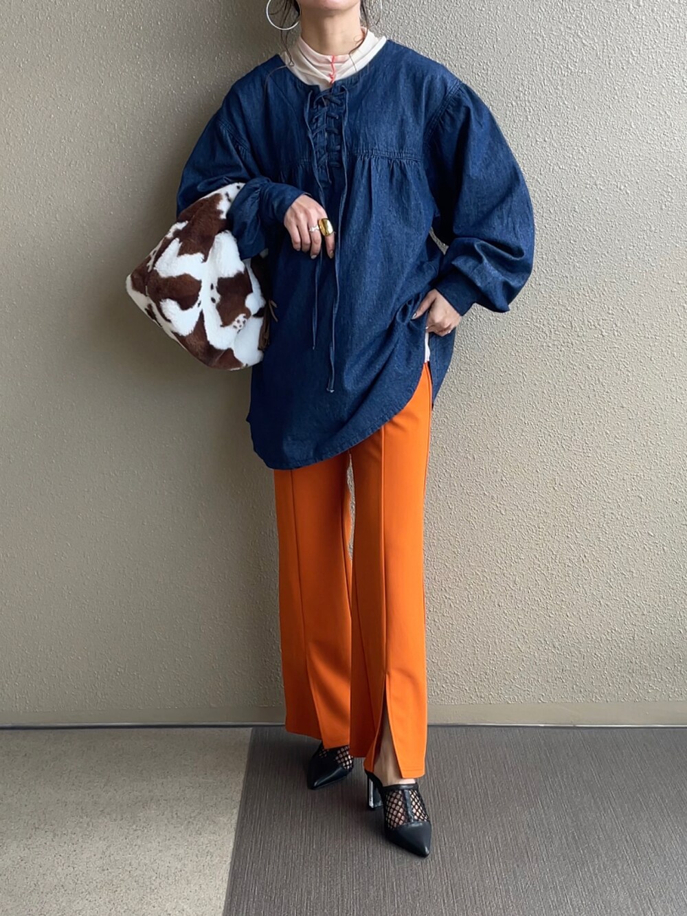 オレンジ系のスラックス、ブラック系のパンプス、ホワイト系のシャツ/ブラウスを着用したレディースの冬コーディネートの3枚目の写真