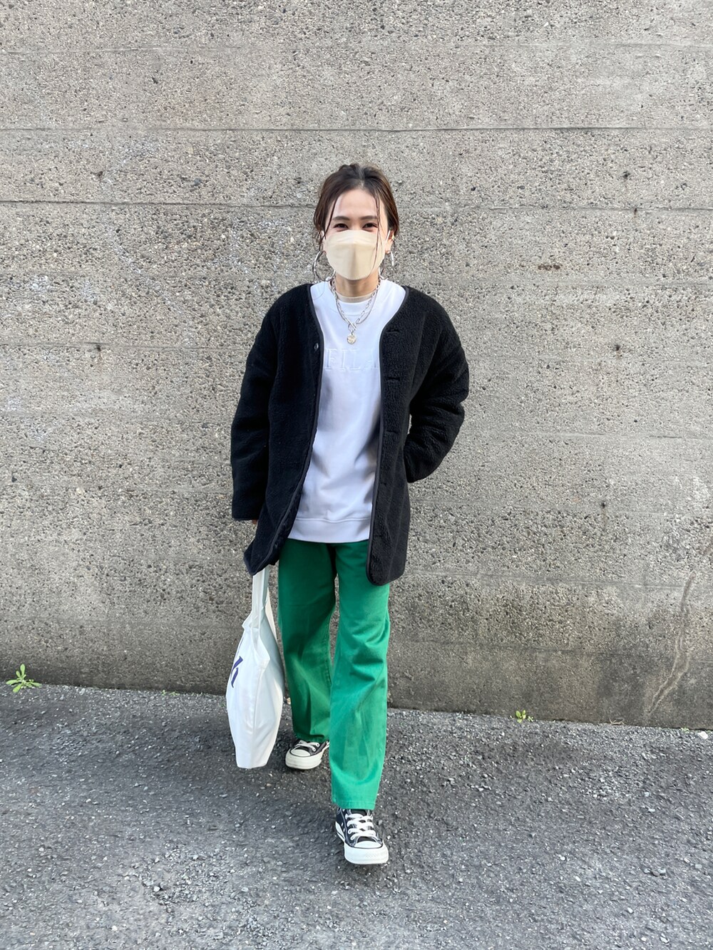 グリーン系のデニムパンツ、ブラック系のブルゾン、ホワイト系のスウェットを着用したレディースの冬コーディネートの3枚目の写真