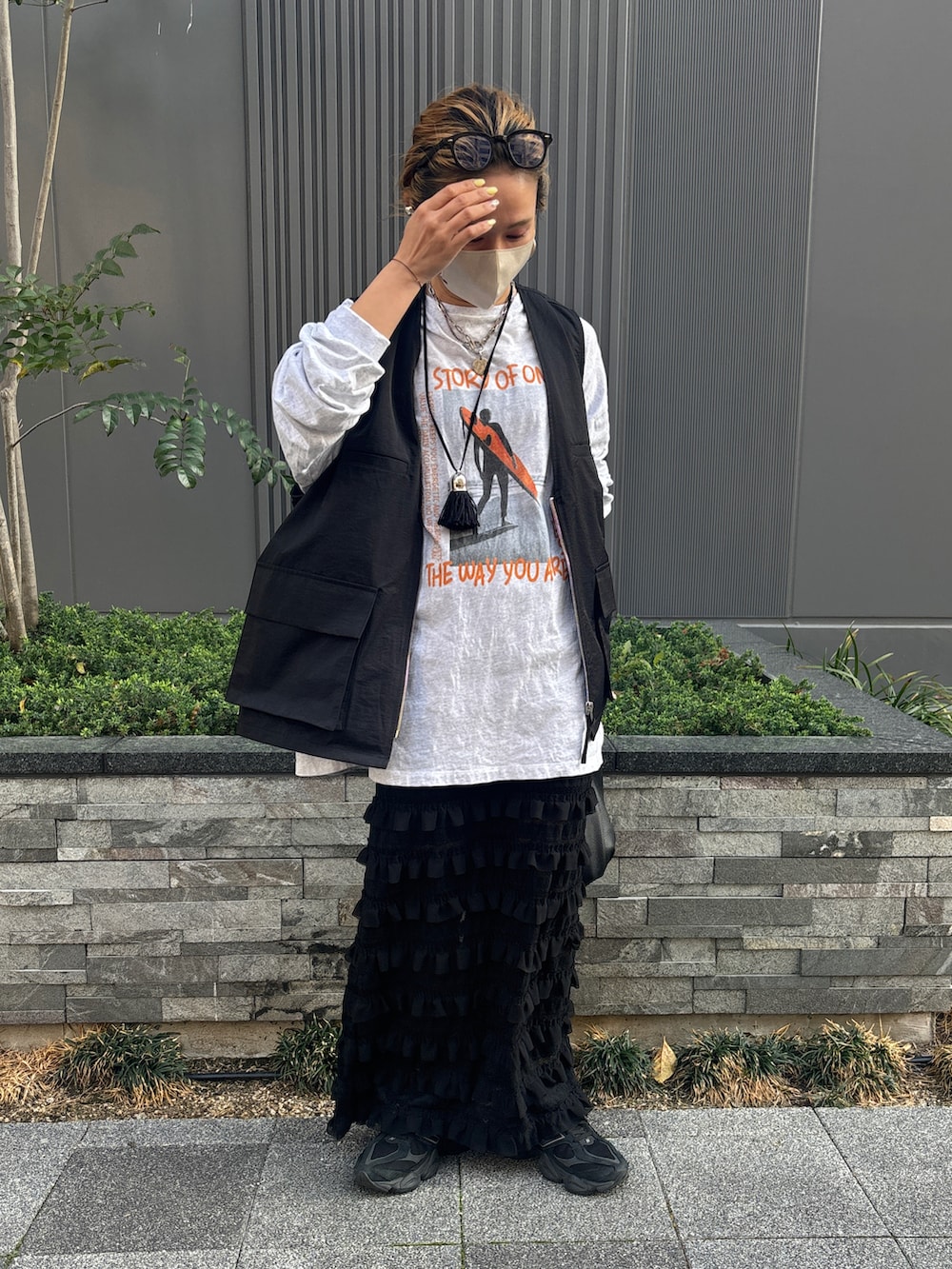 グレー系のTシャツ/カットソー、ブラック系のベスト、ブラック系のスカートを着用したレディースの春コーディネートの2枚目の写真