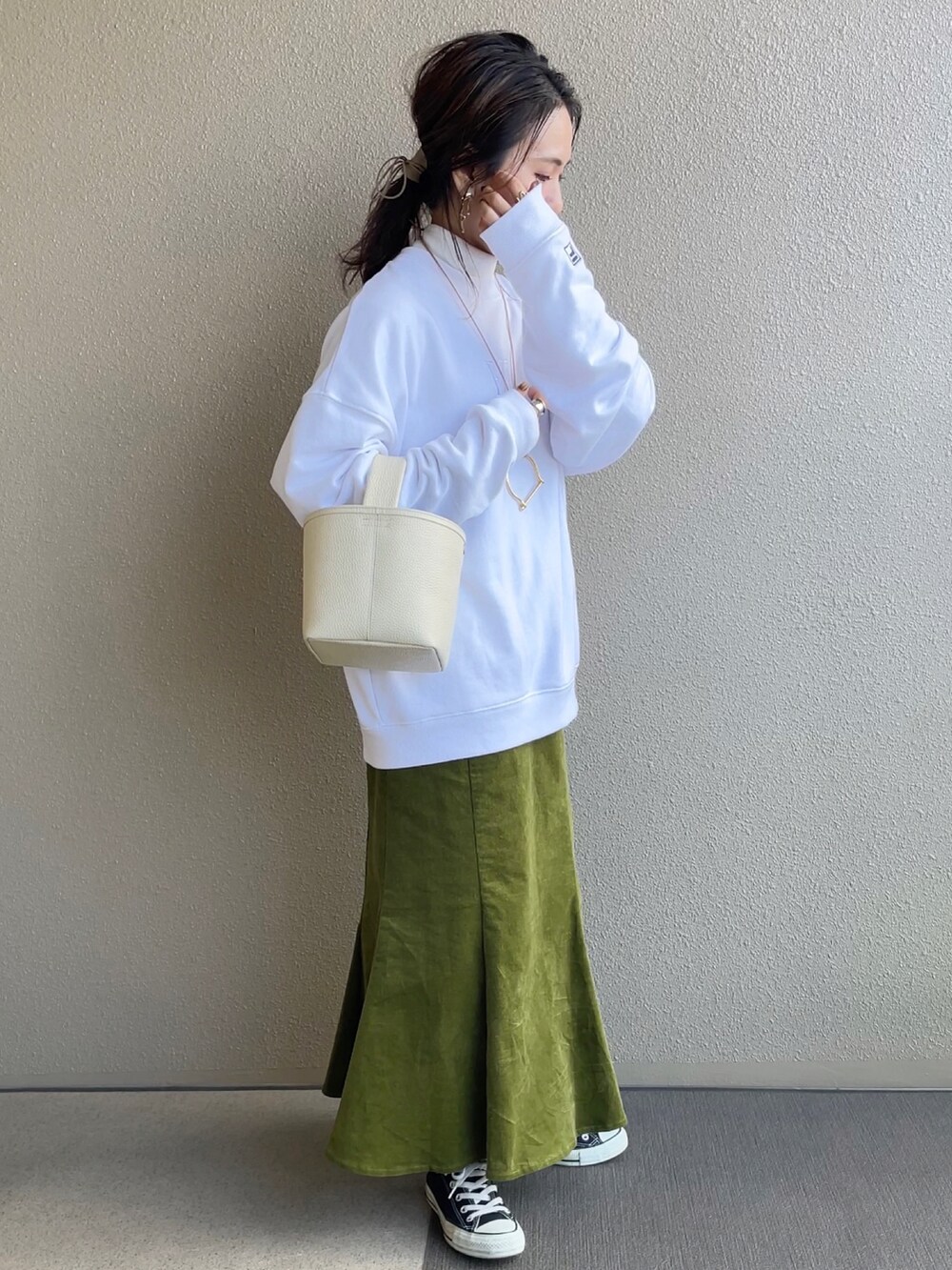 グリーン系のスカート、ホワイト系のスウェット、ブラック系のその他アウターを着用したレディースの冬コーディネートの2枚目の写真