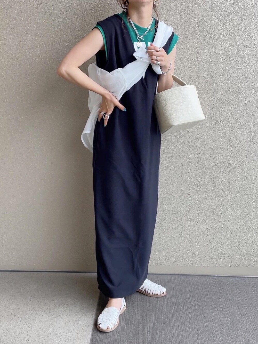 ブラック系のジャンパースカート、ホワイト系のトップス、ホワイト系のニット/セーターを着用したレディースの春コーディネートの2枚目の写真