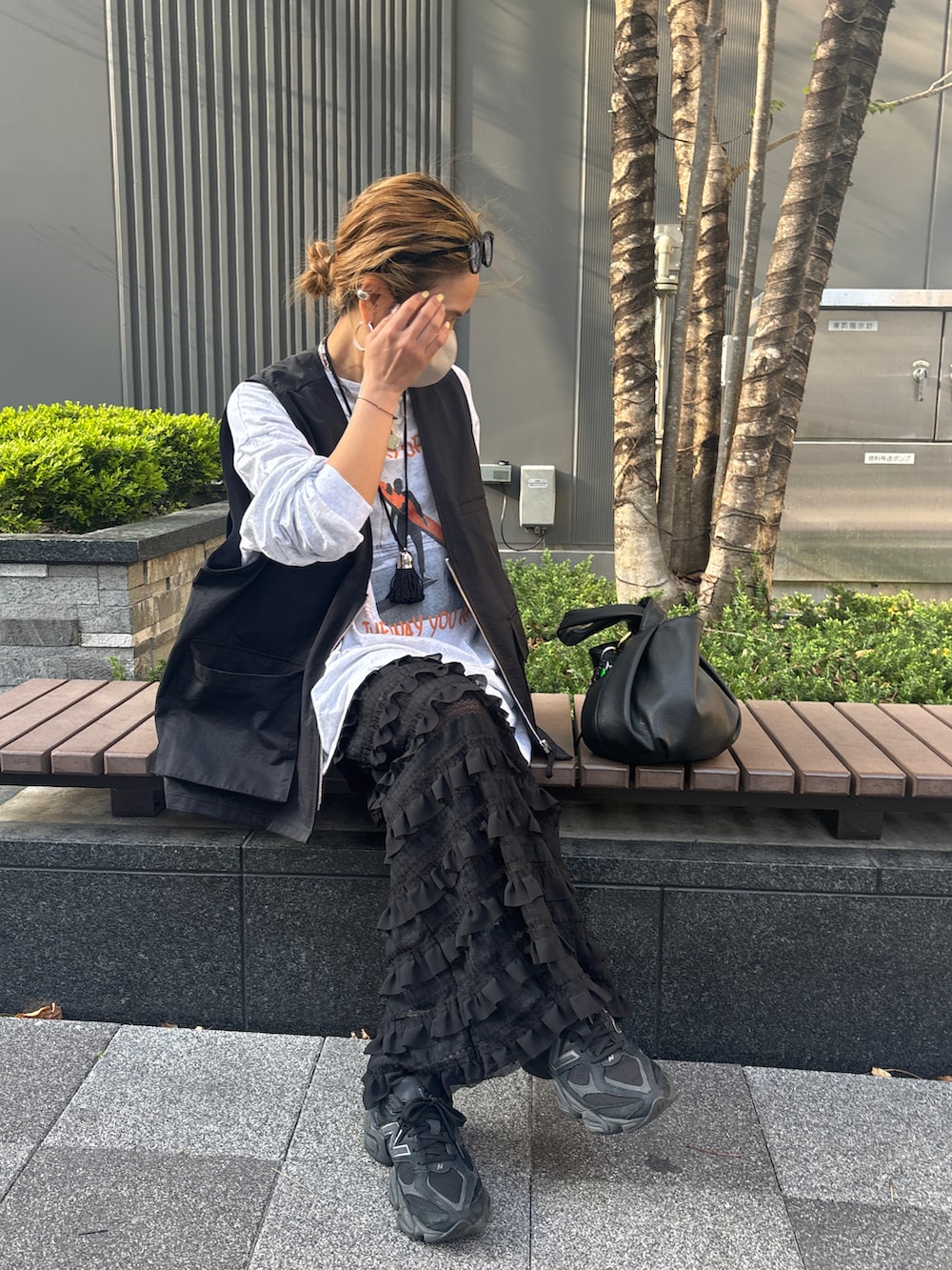 グレー系のTシャツ/カットソー、ブラック系のベスト、ブラック系のスカートを着用したレディースの春コーディネートの4枚目の写真